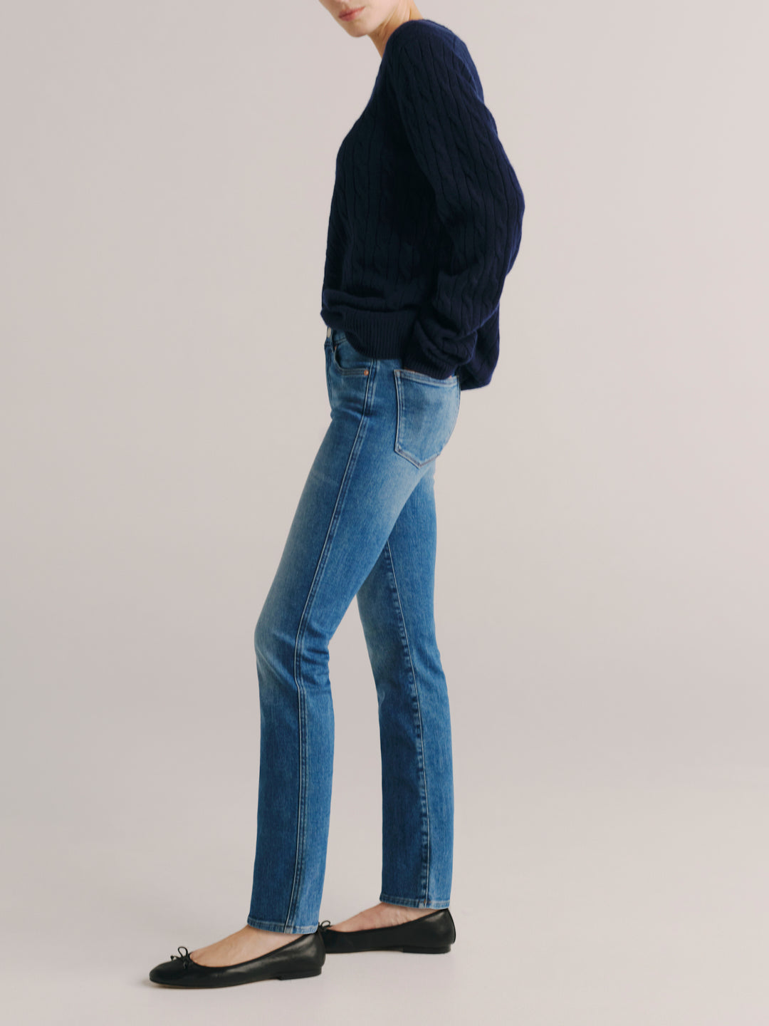 Mara jeans in Crisp Air with a navy cable-knit sweater, full-length side profile in a studio.