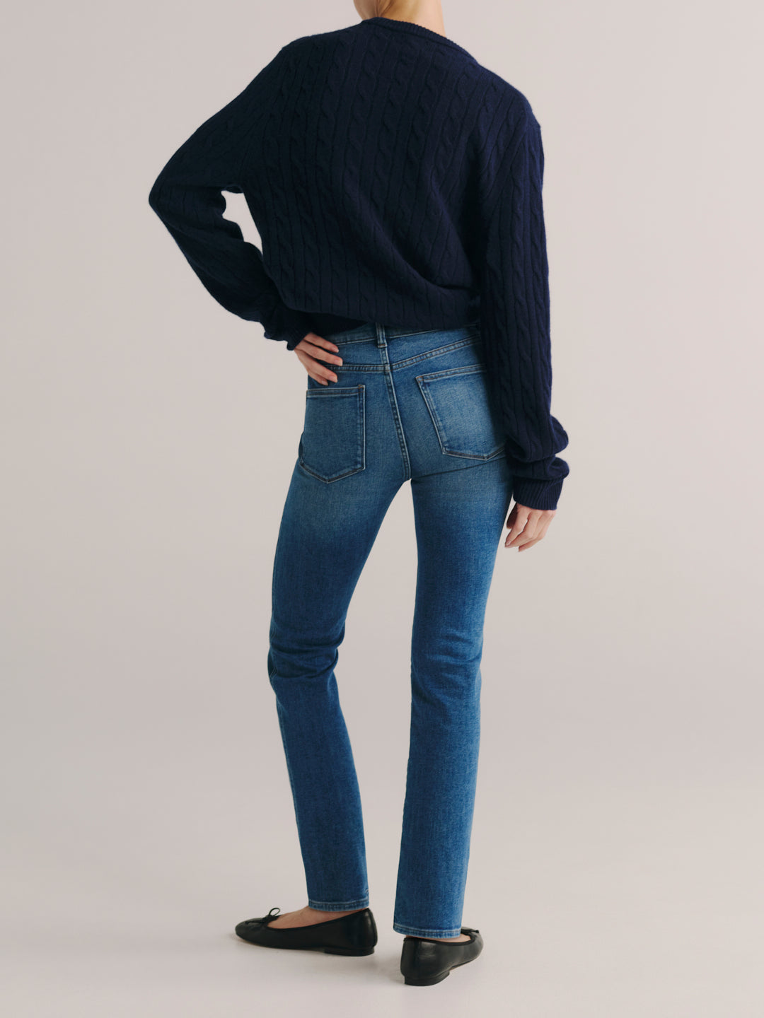 Mara jeans in Crisp Air with a navy cable-knit sweater, full-length back view in a studio.