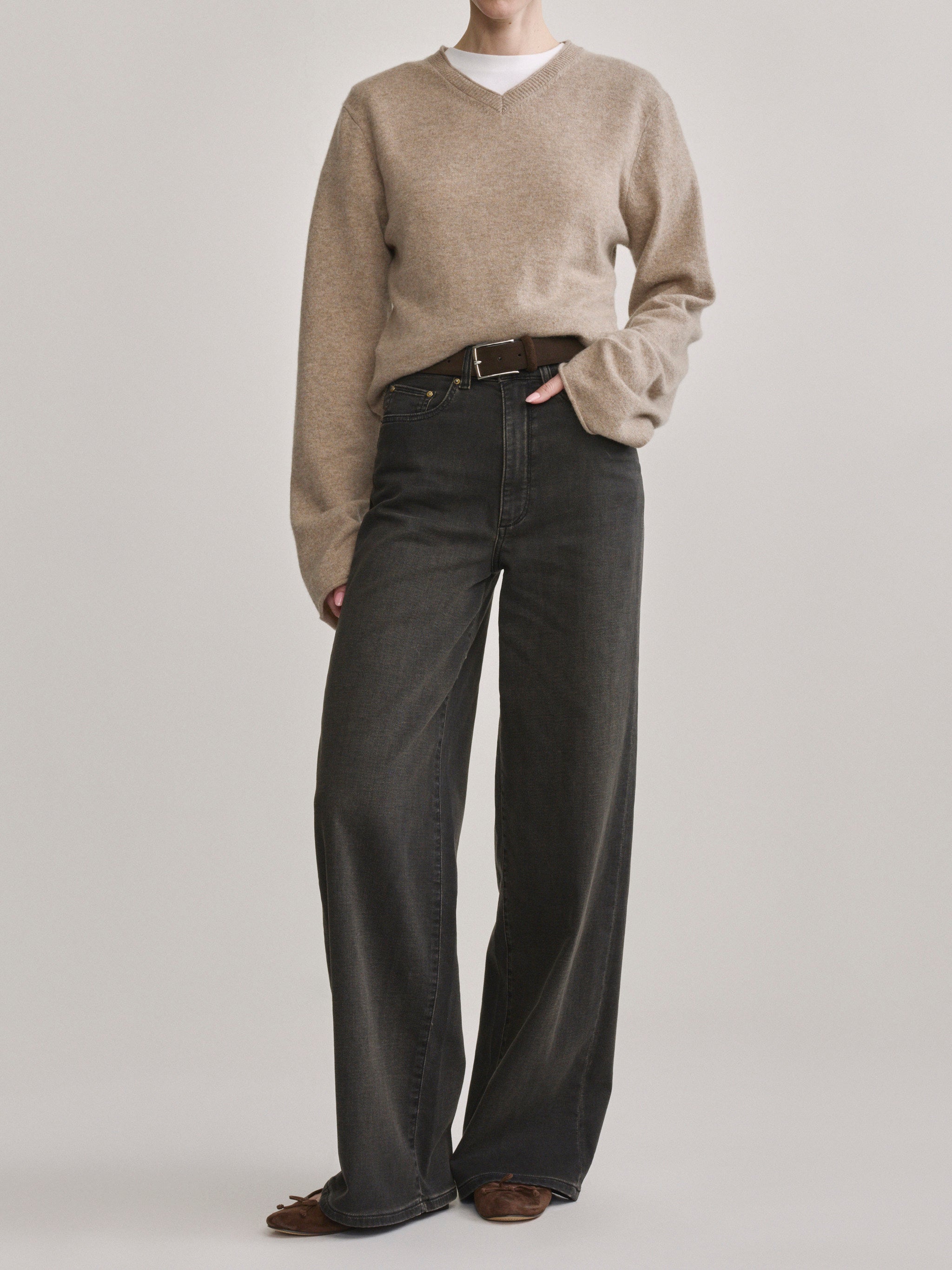 DL1961 Hepburn wide-leg high-rise jeans in washed black 'Rock', front view with camel sweater and belt.