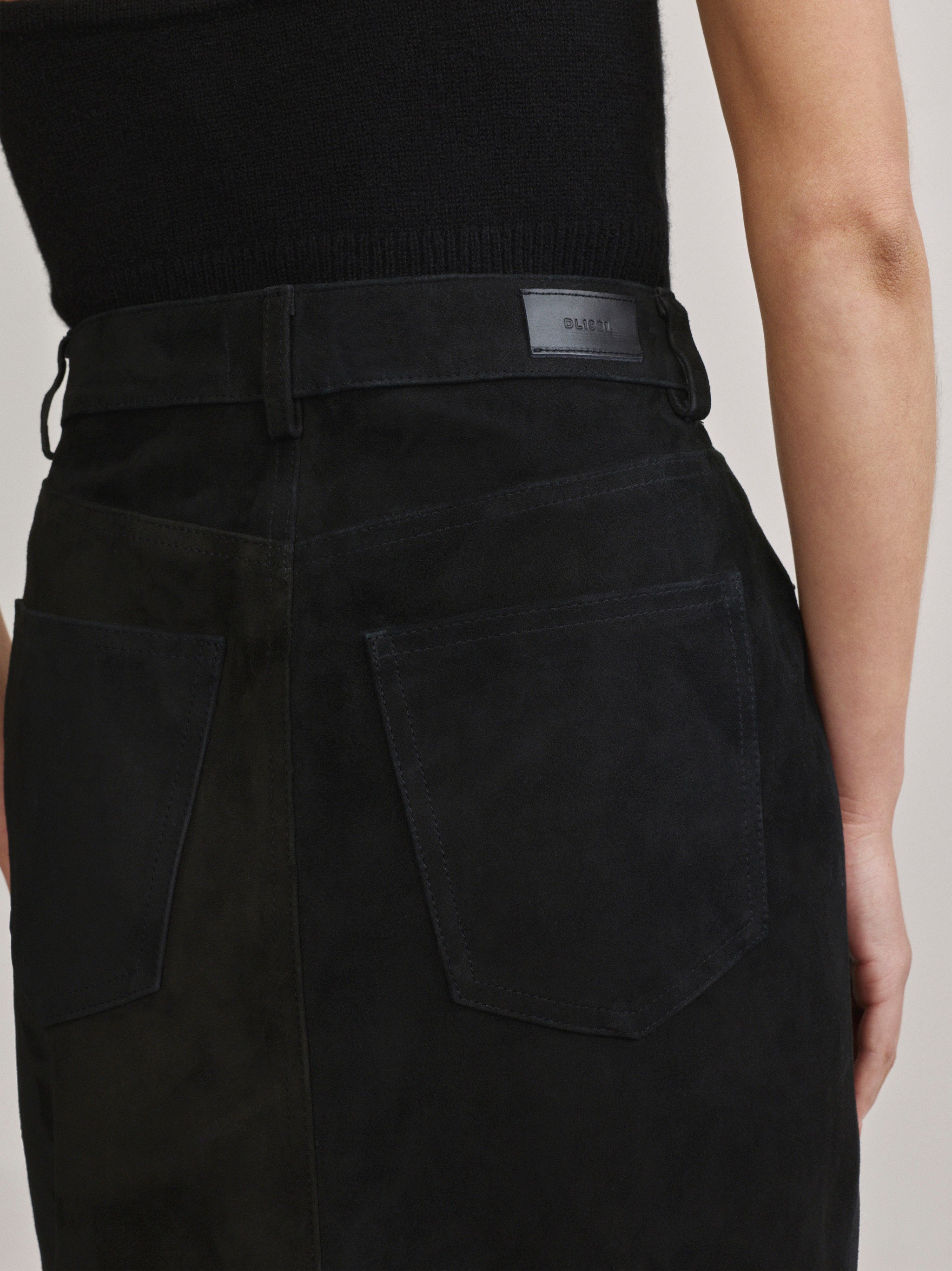 DL1961 Alma Suede Midi Skirt in Black Suede, close-up of back pocket and logo tab.
