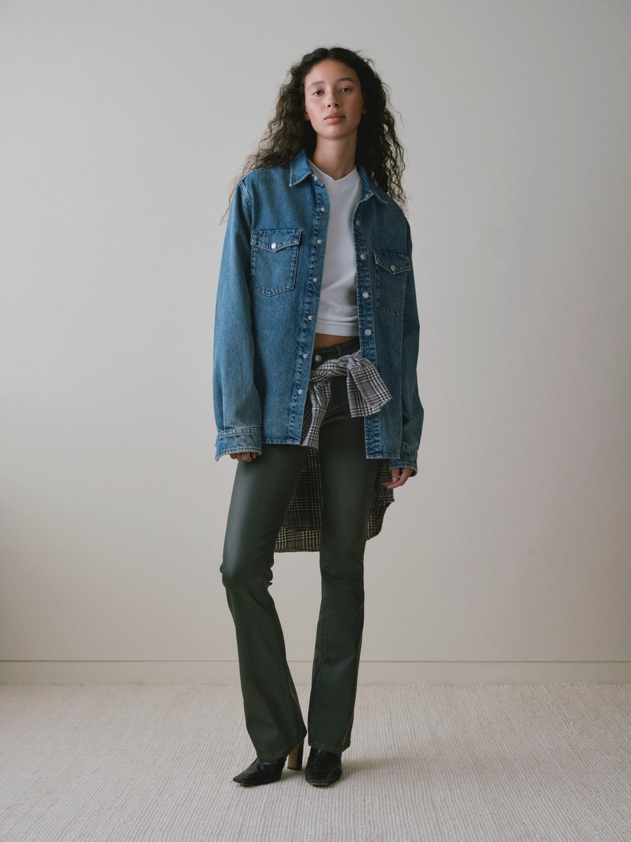 DL1961 women's Milano Slim Boot Low Rise Instasculpt jeans in coated dark olive 'Dark Pine Coated', front view with an oversized denim shirt.