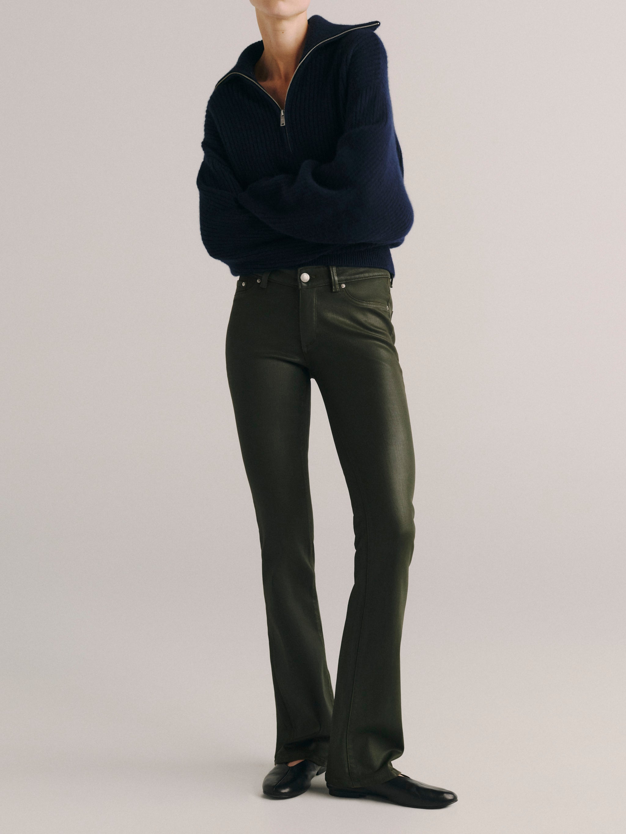 DL1961 women's Milano Slim Boot Low Rise Instasculpt jeans in coated dark olive 'Dark Pine Coated', front view with a navy half-zip sweater.