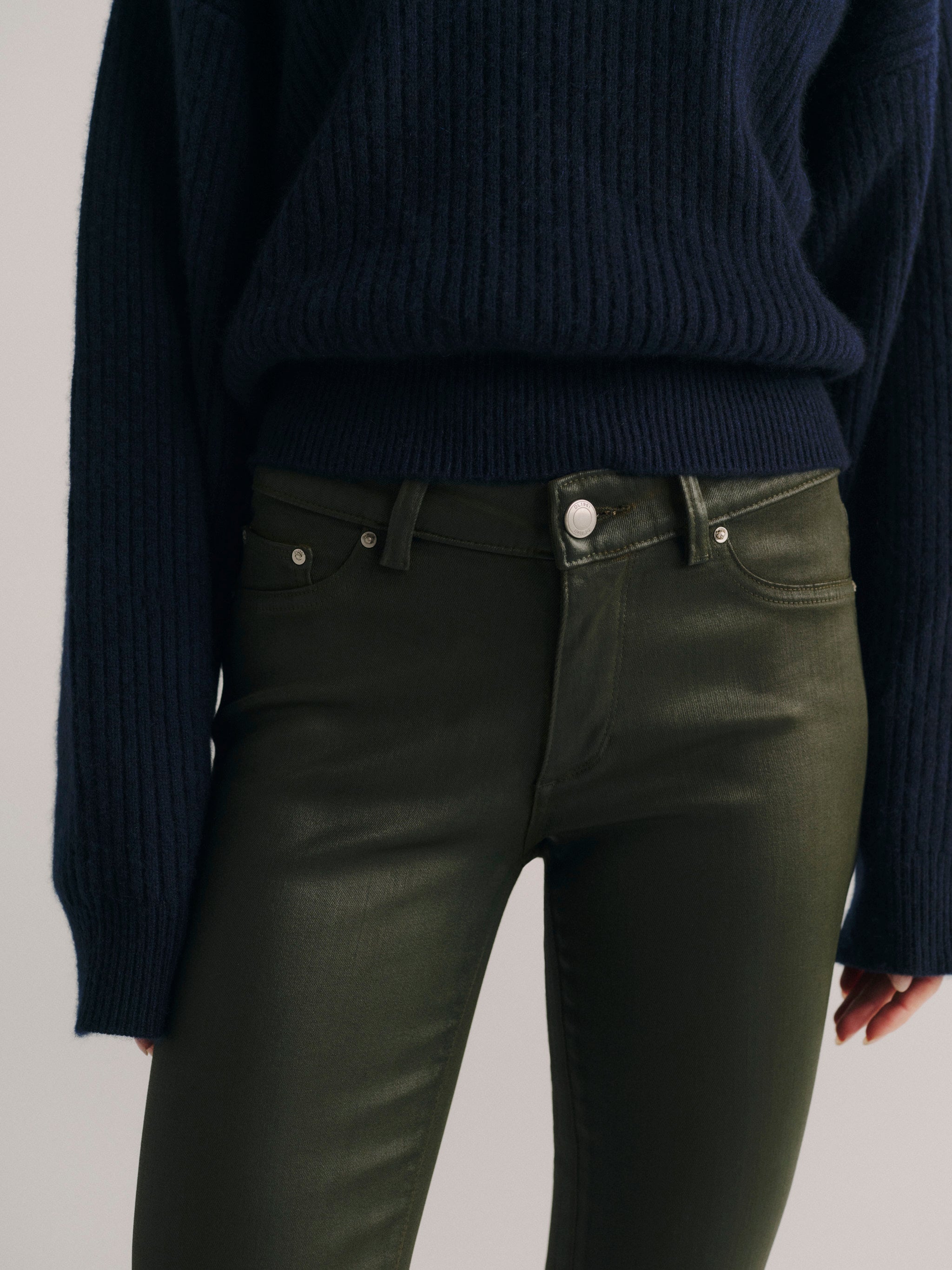 DL1961 women's Milano Slim Boot Low Rise Instasculpt jeans in coated dark olive 'Dark Pine Coated', close-up of the waist showing the coated sheen.