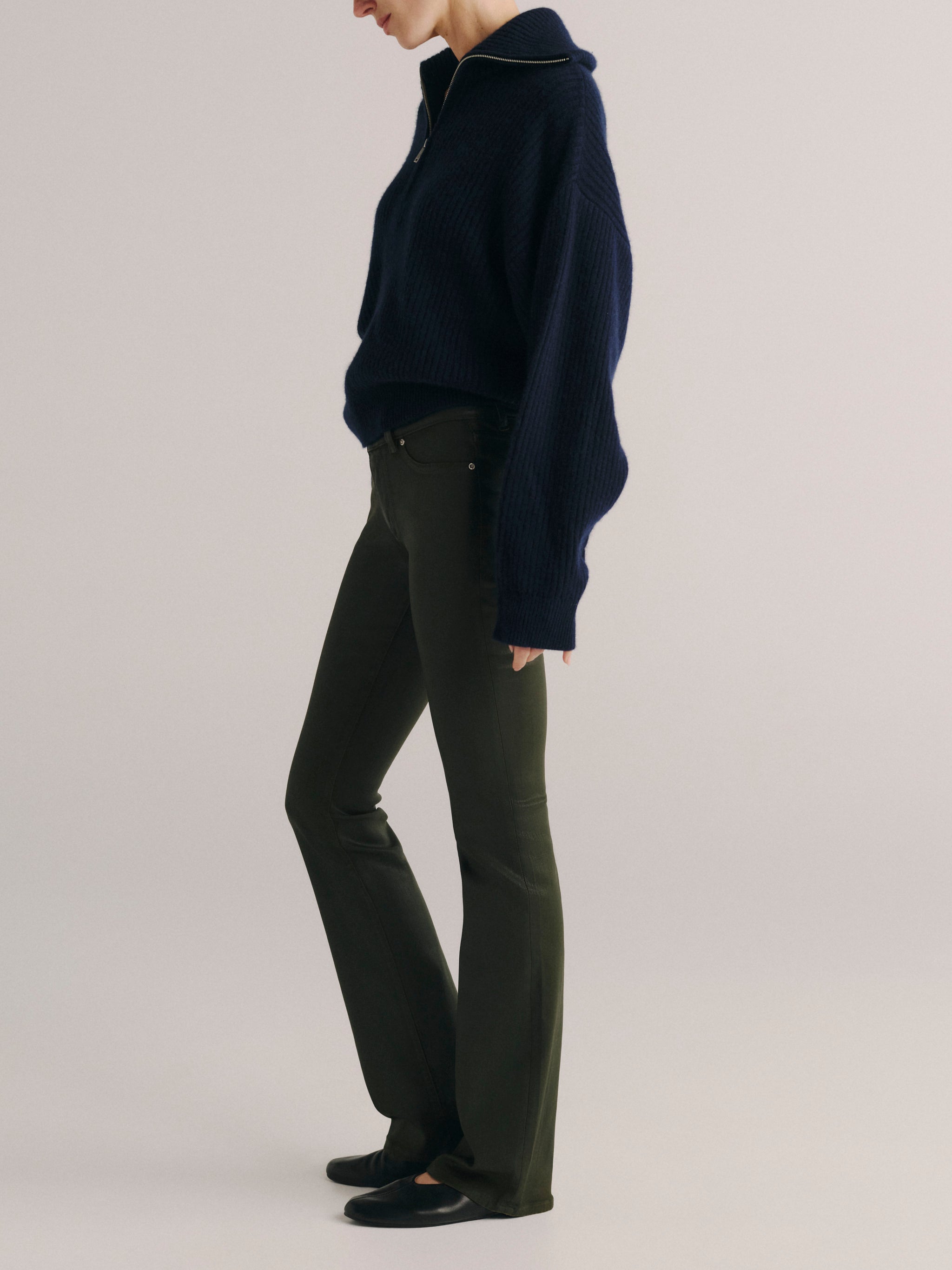 DL1961 women's Milano Slim Boot Low Rise Instasculpt jeans in coated dark olive 'Dark Pine Coated', side profile showing the bootcut leg.