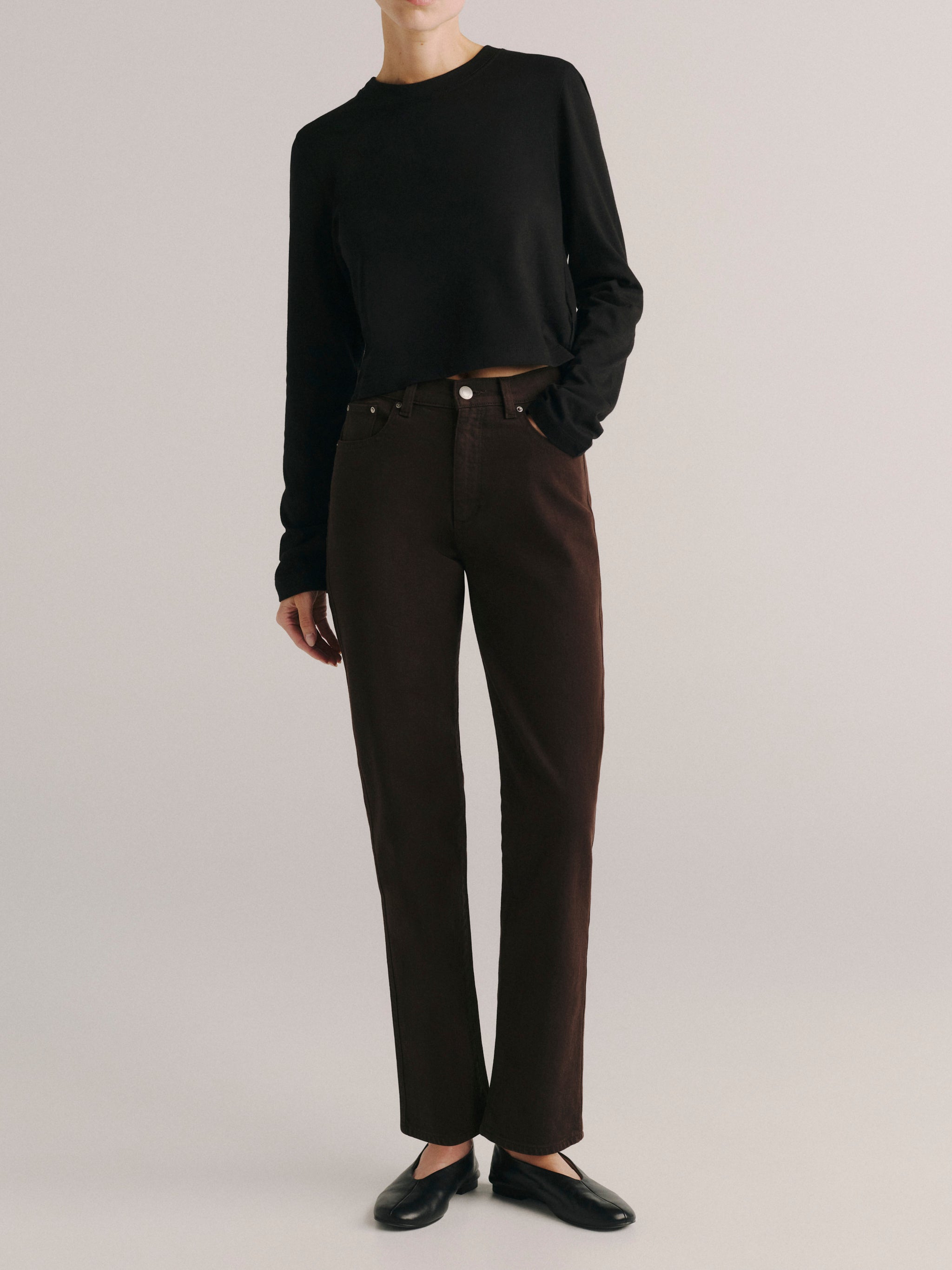 DL1961 women's Cate Stretch Straight High-Rise jeans in dark brown 'Tobacco', front view with a black knit top and flats.