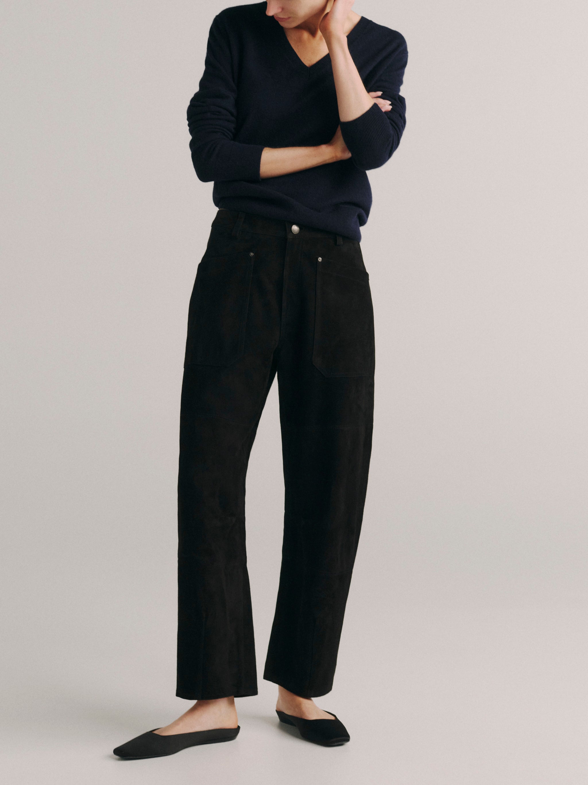 DL1961 women's Bilie Easy Barrel suede pants in black, front view with a navy V-neck sweater and black flats.