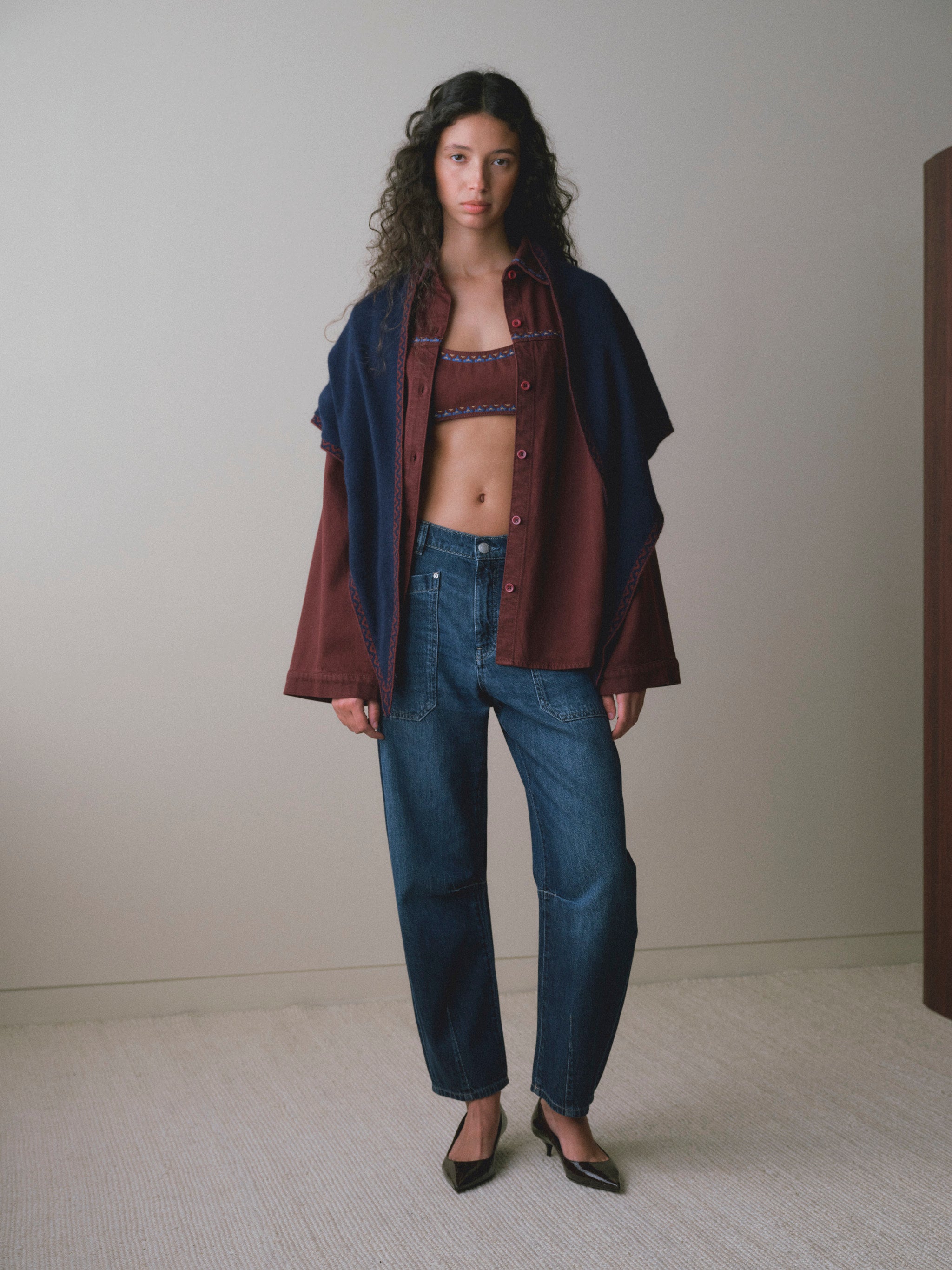 DL1961 women's Colette denim bralette in 'Burgundy Embroidery', full-length front view under an open overshirt with blue jeans.