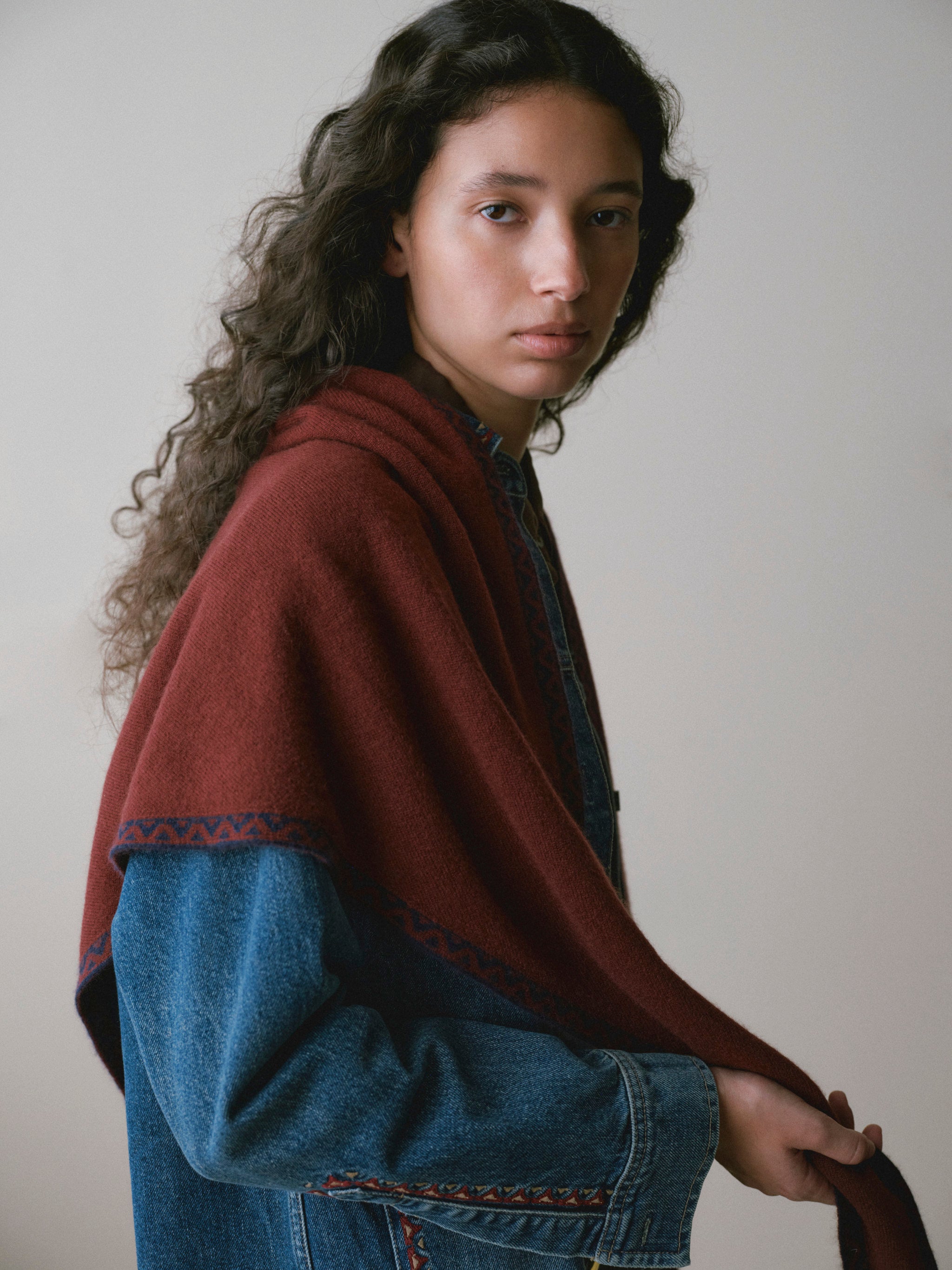 DL1961 Après-Ski scarf in burgundy with navy trim, draped over a denim jacket, side view.
