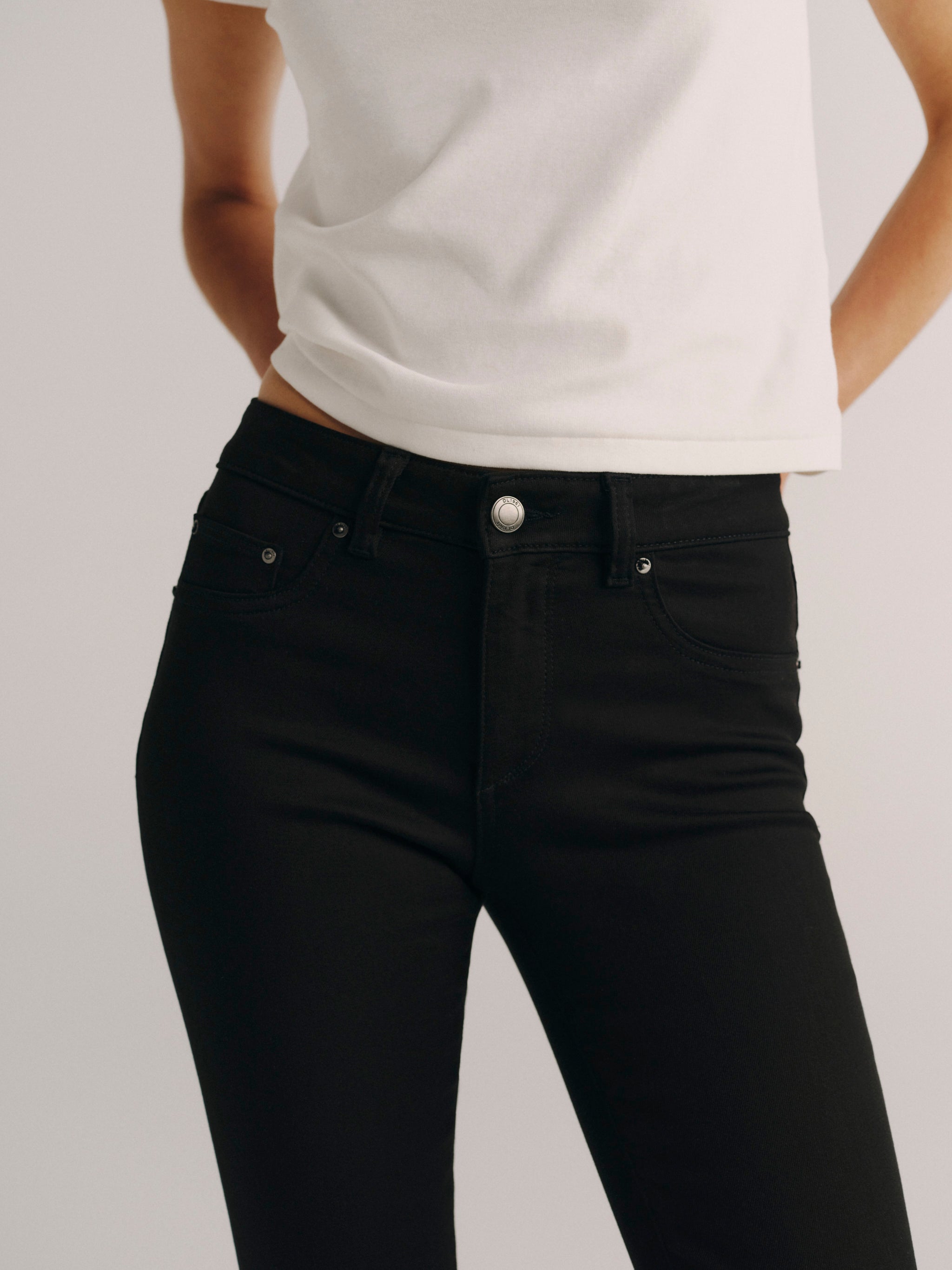 DL1961 women's Jessica Skinny Low-Rise Instasculpt jeans in black 'Cascade', close-up of the waist, button and front pocket.