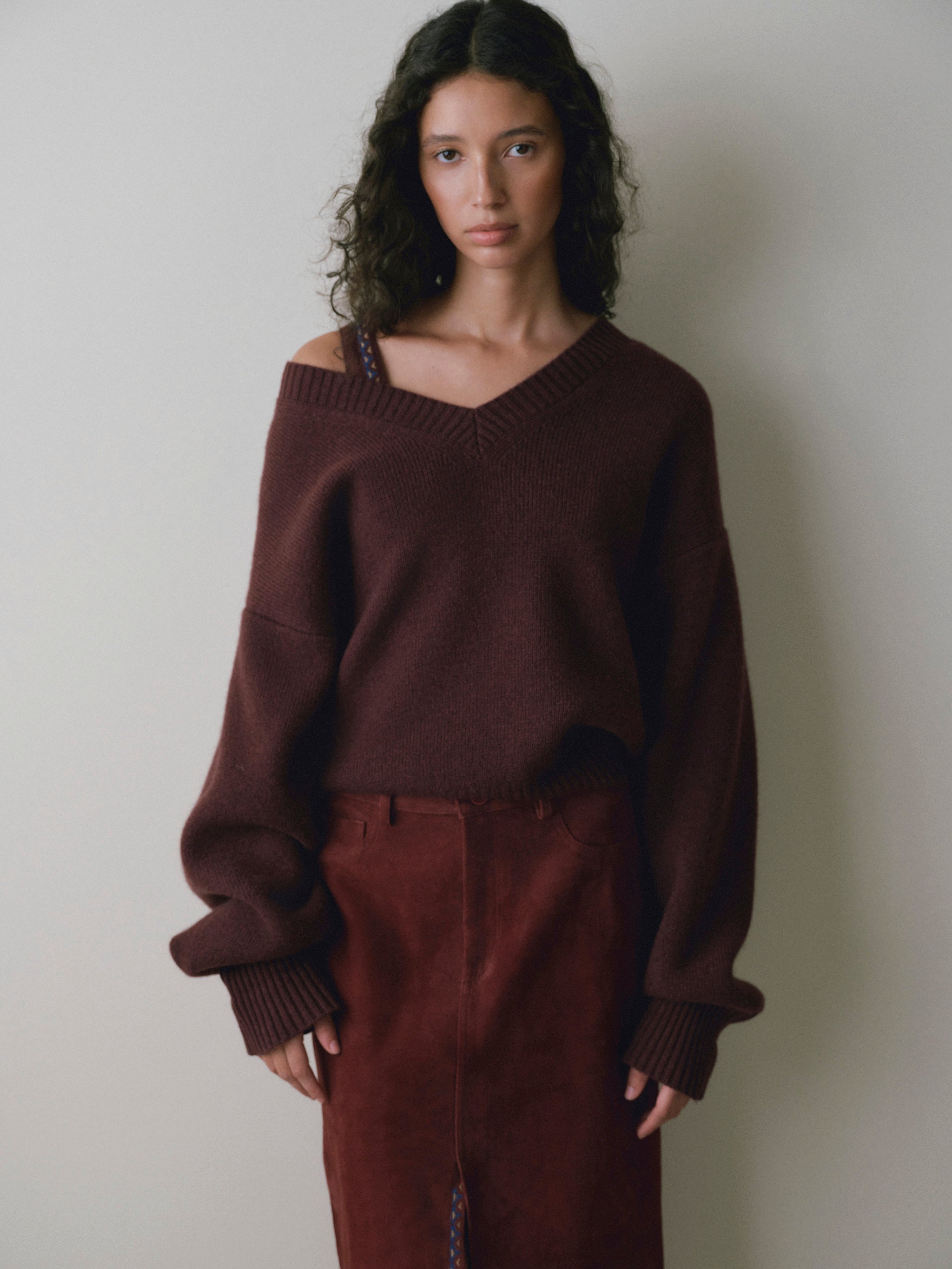 DL1961 women's Robbie oversized V-neck sweater in bordeaux, front view with a burgundy suede skirt.