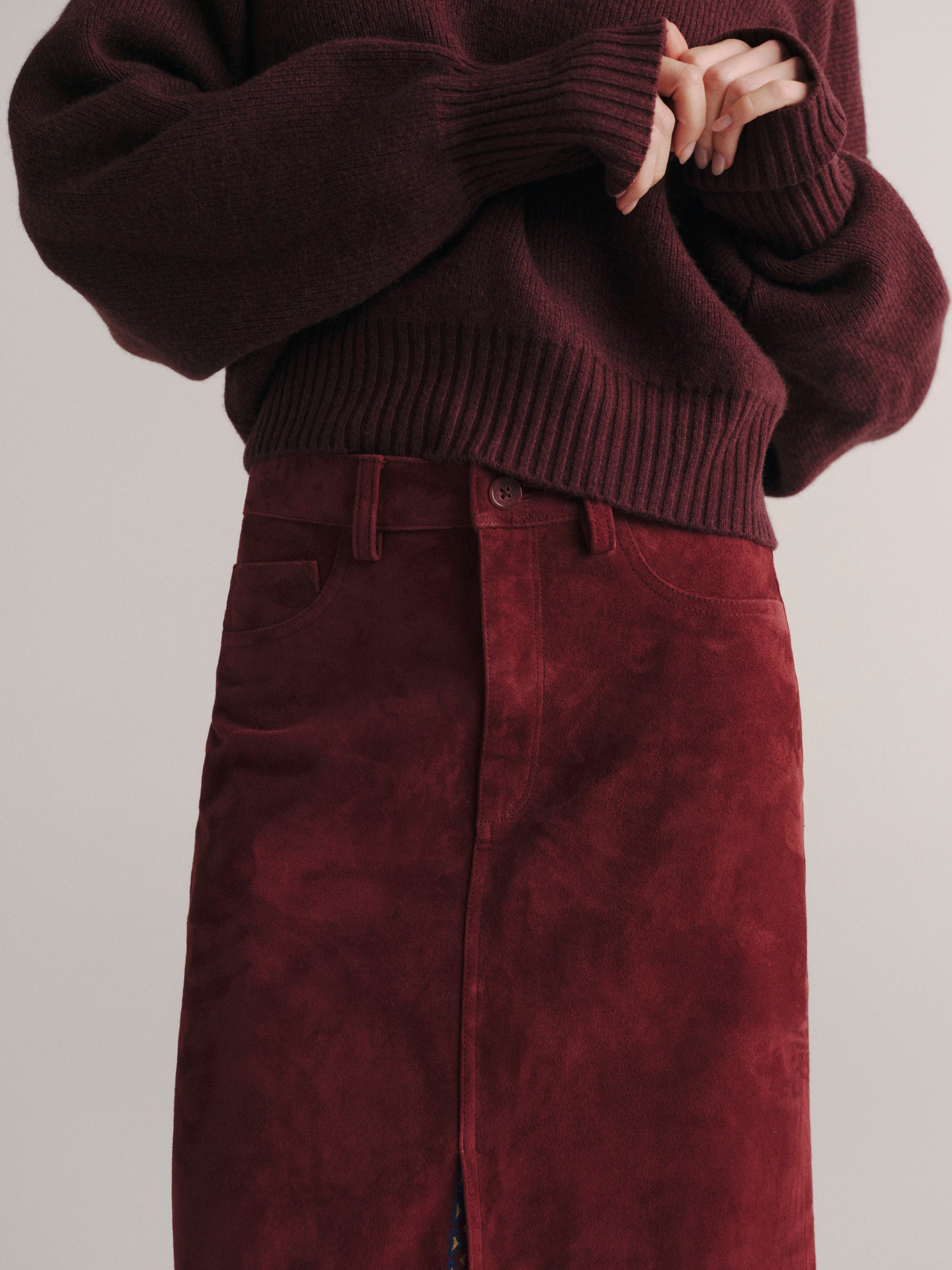 DL1961 women's Alma suede midi skirt in 'Burgundy Suede Embroidery', close-up of the waist, belt loops and front slit.