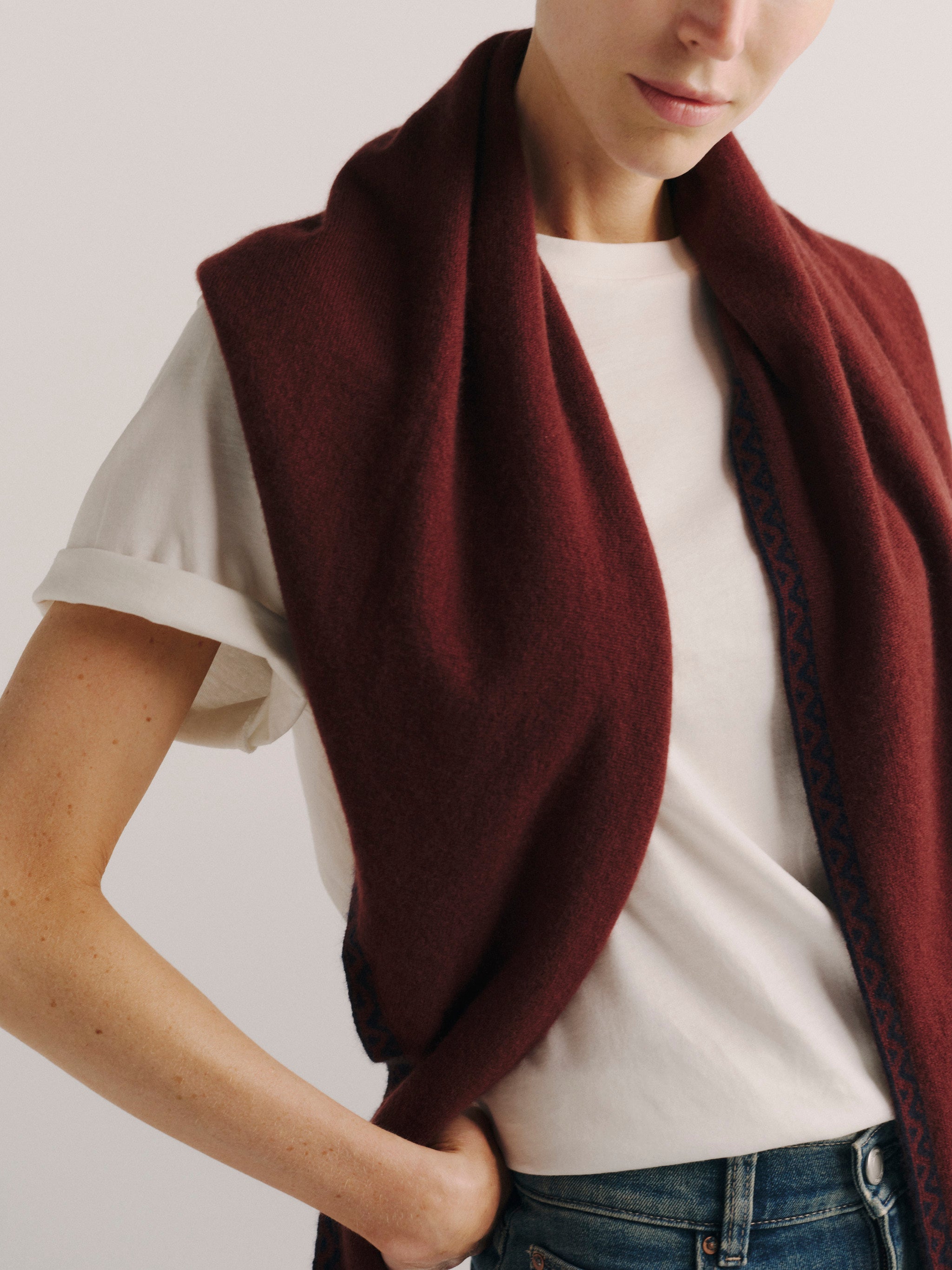 DL1961 Après-Ski scarf in burgundy with navy trim, worn wrapped around the neck with the ends falling forward.