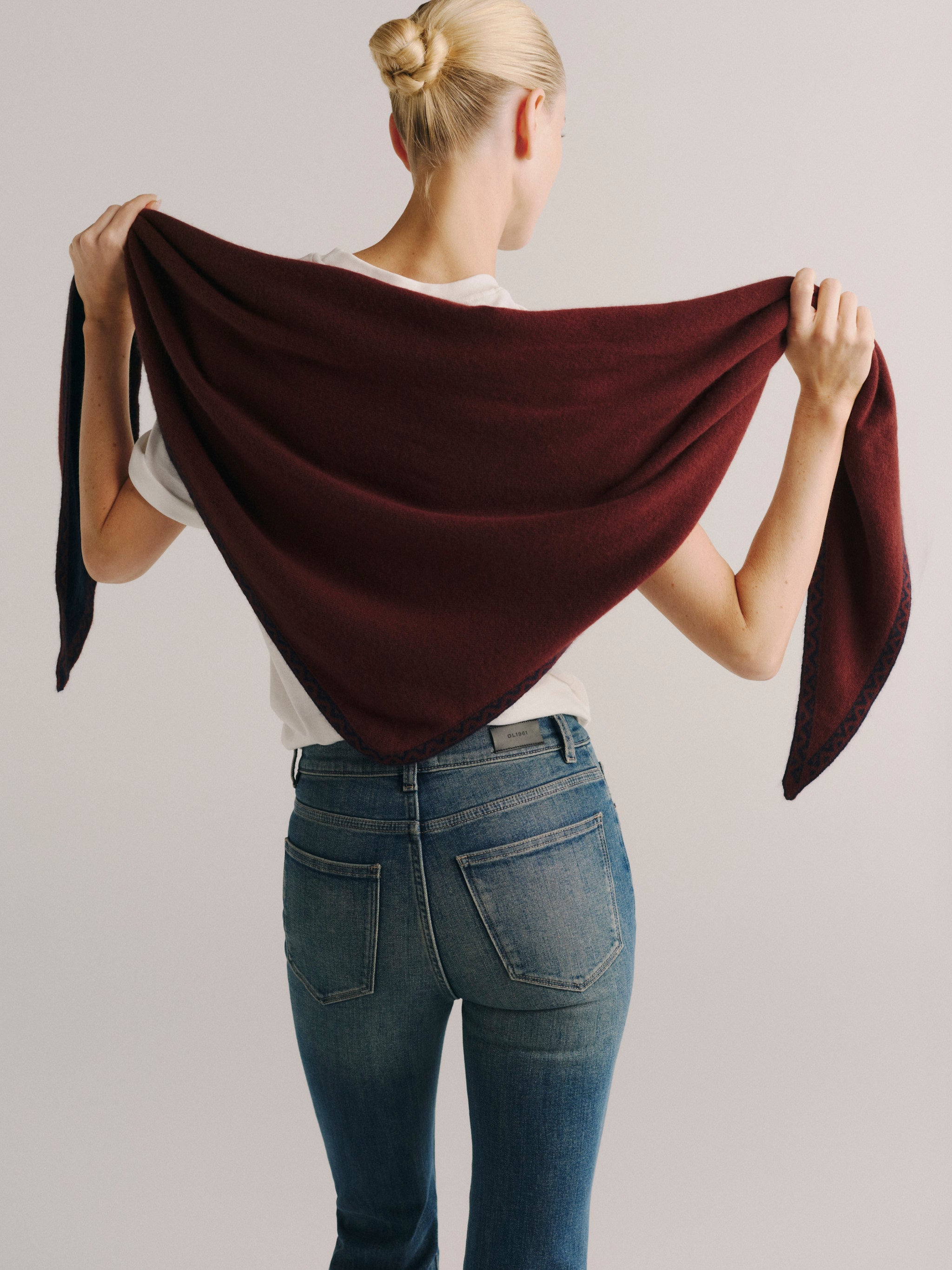 DL1961 Après-Ski scarf in burgundy with navy trim, held open to show the triangular wrap shape.