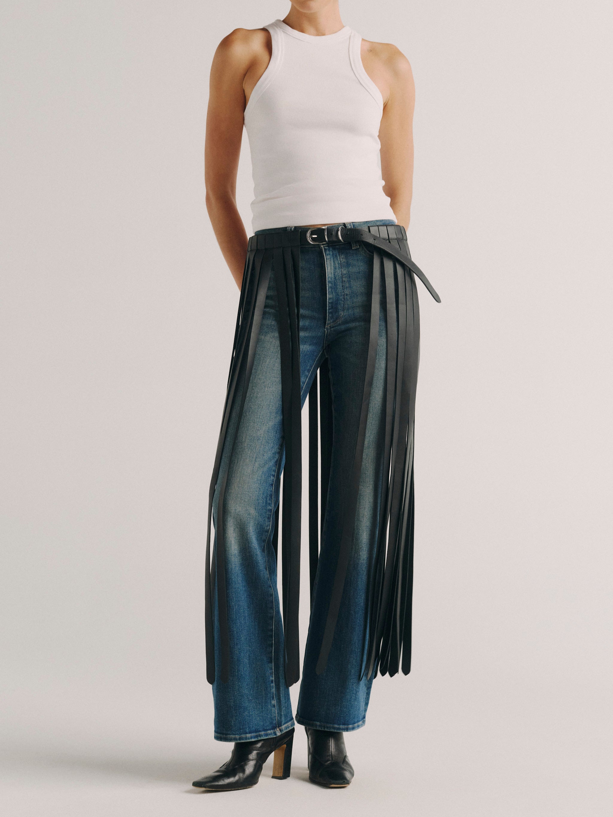DL1961 fringe leather belt in black, front view worn over wide leg jeans with a white tank.
