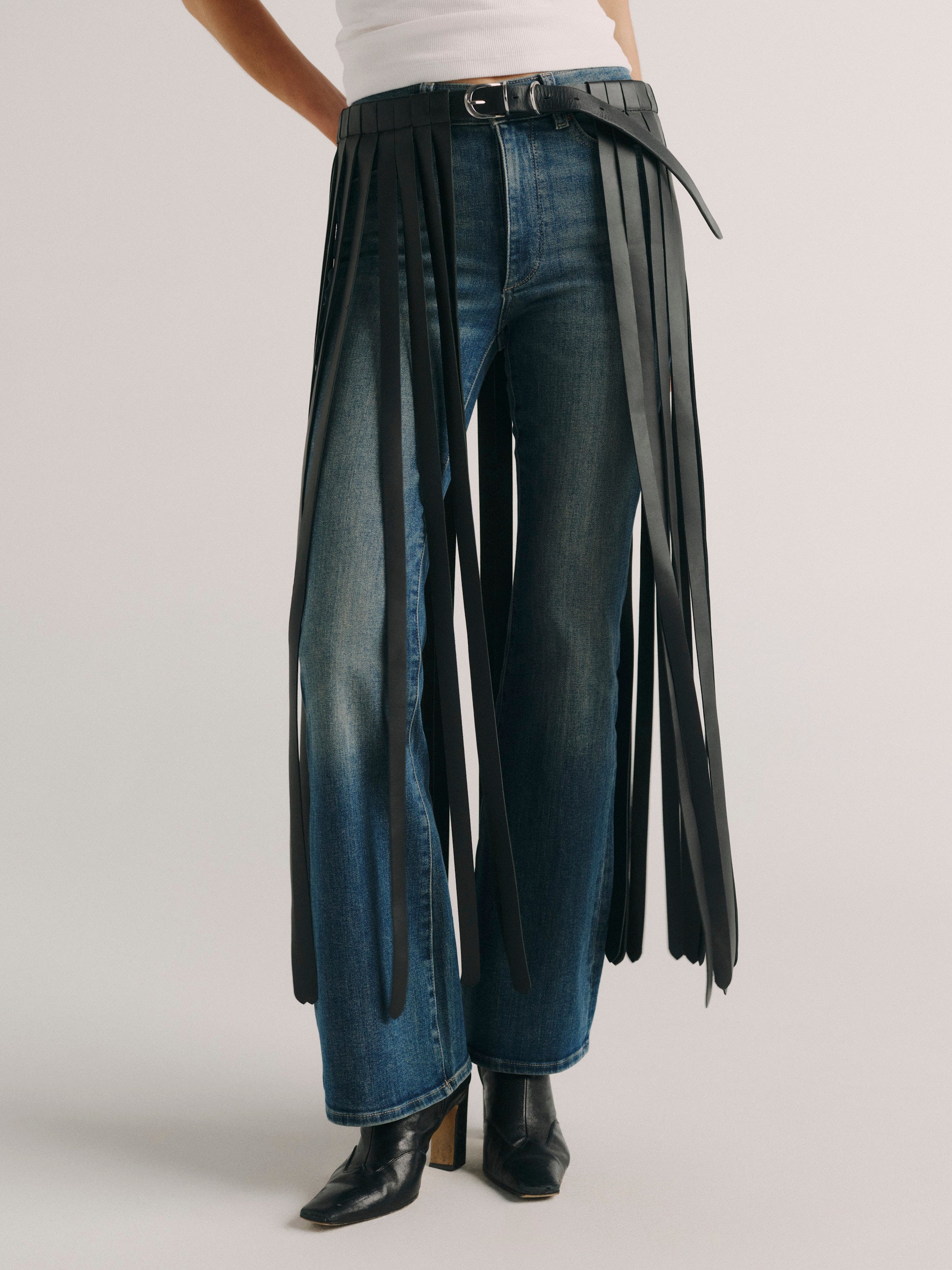 DL1961 fringe leather belt in black, close-up of the buckle and long fringe panels over denim.