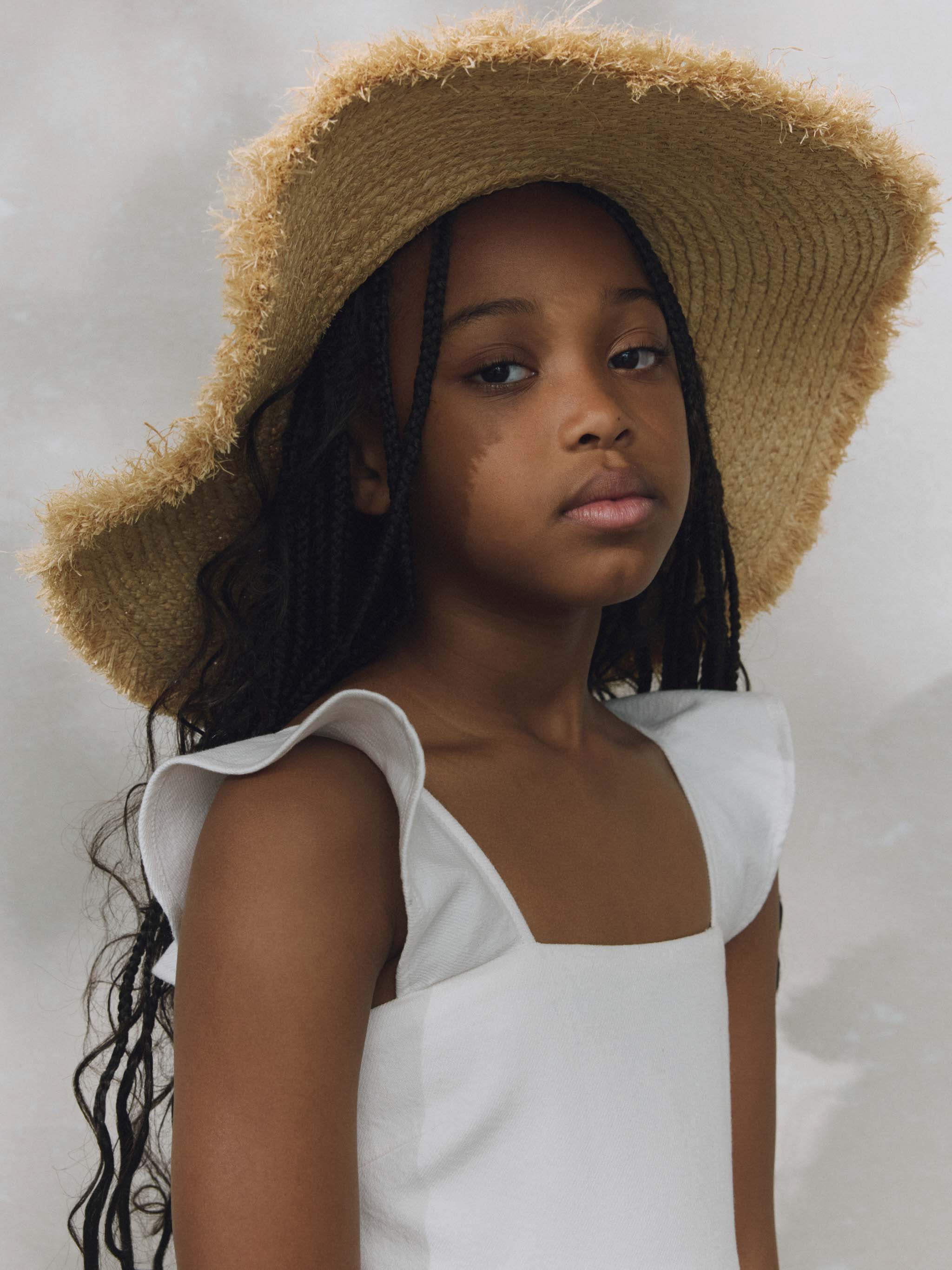 Girl wearing white ruffled dress on plain background.
