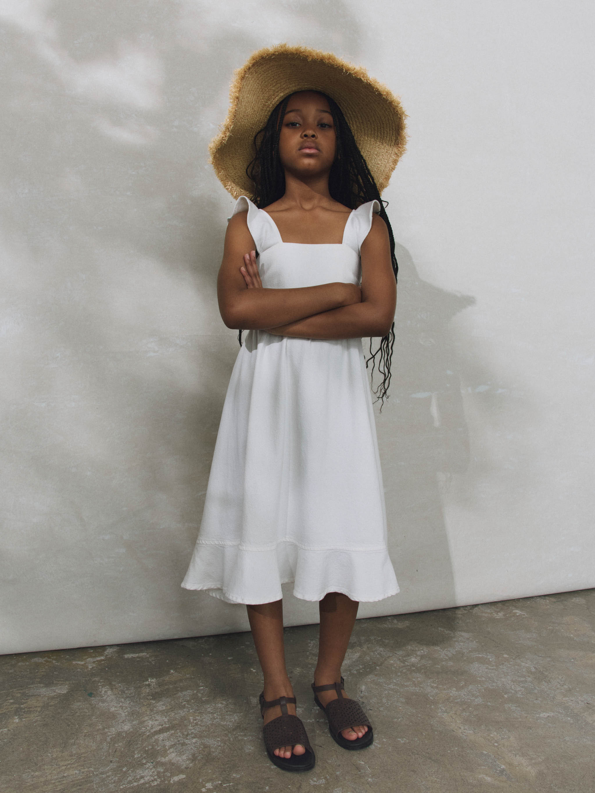 Girl wearing white ruffled dress on plain background.