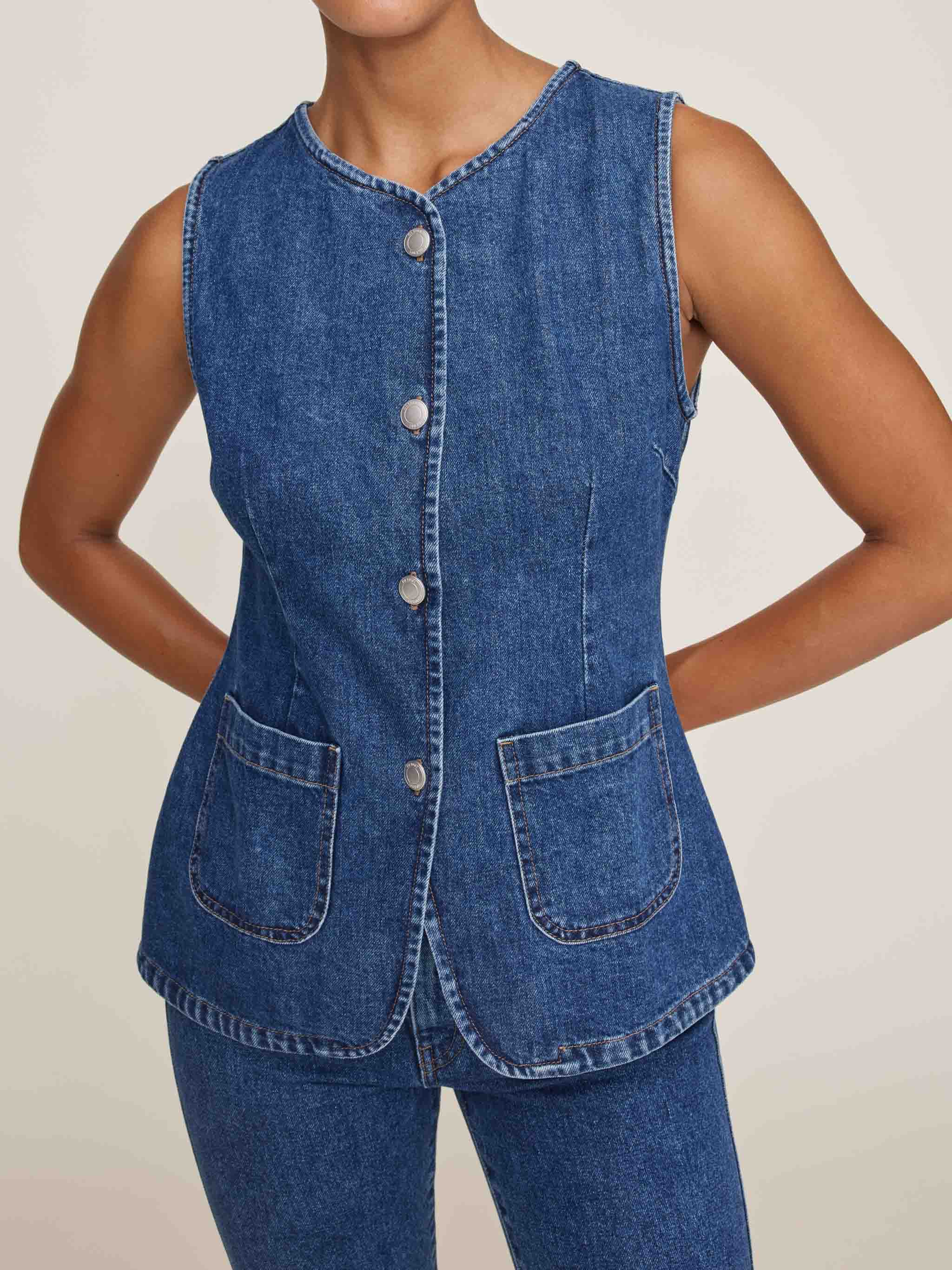 Denim vest with button details on a plain background