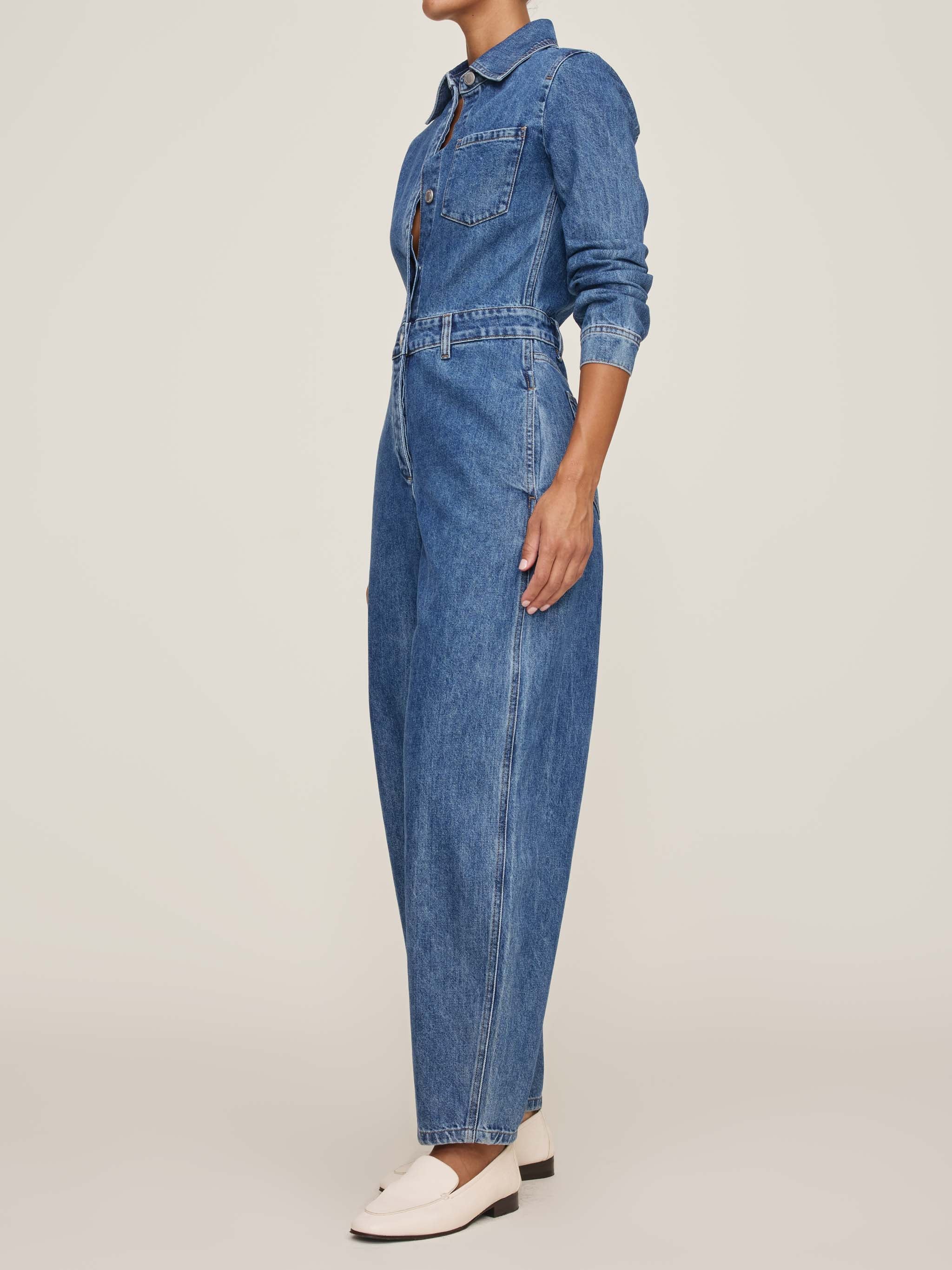 Denim jumpsuit worn by a person on a plain background