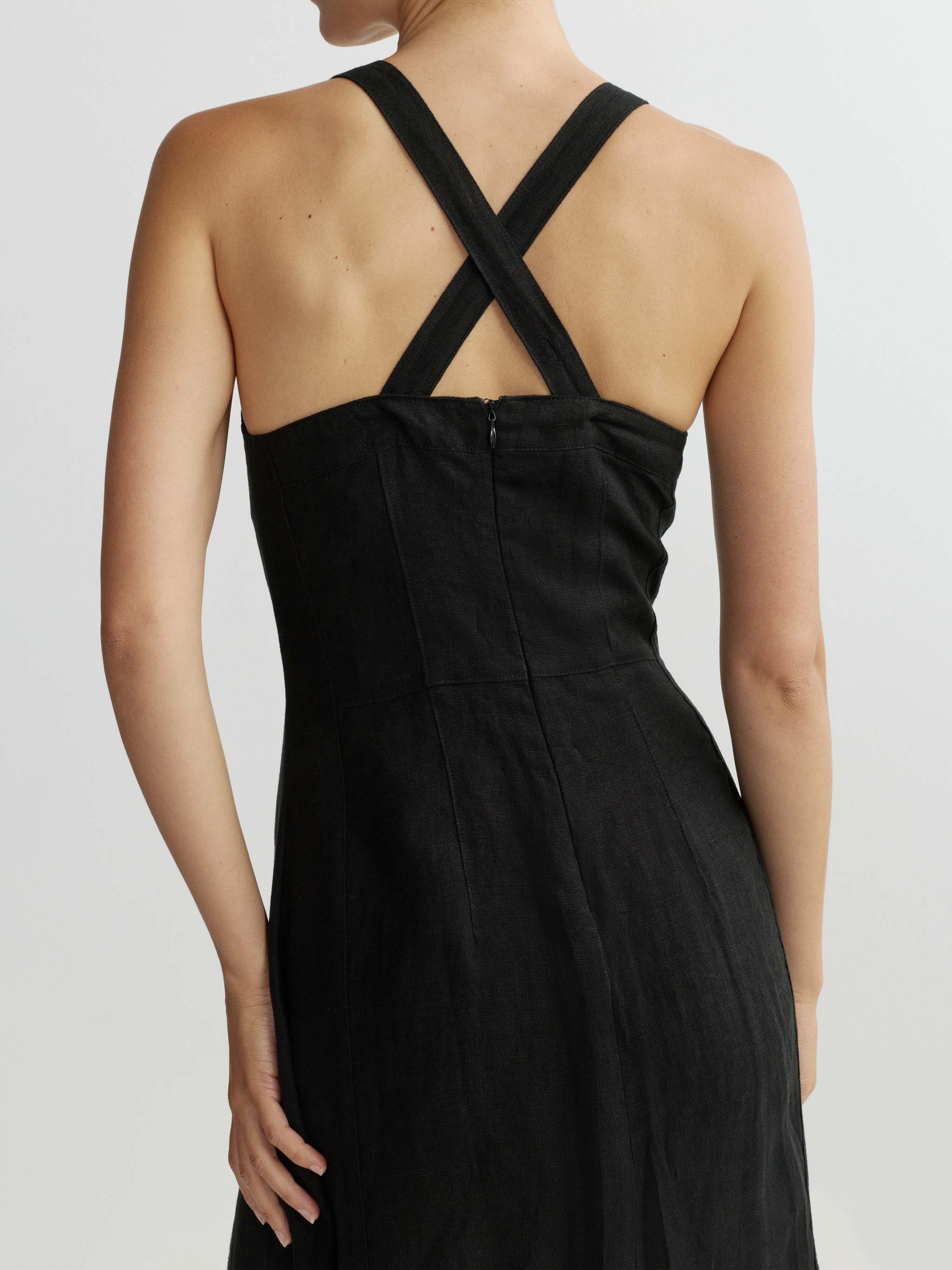 Black dress with criss-cross straps on a plain background