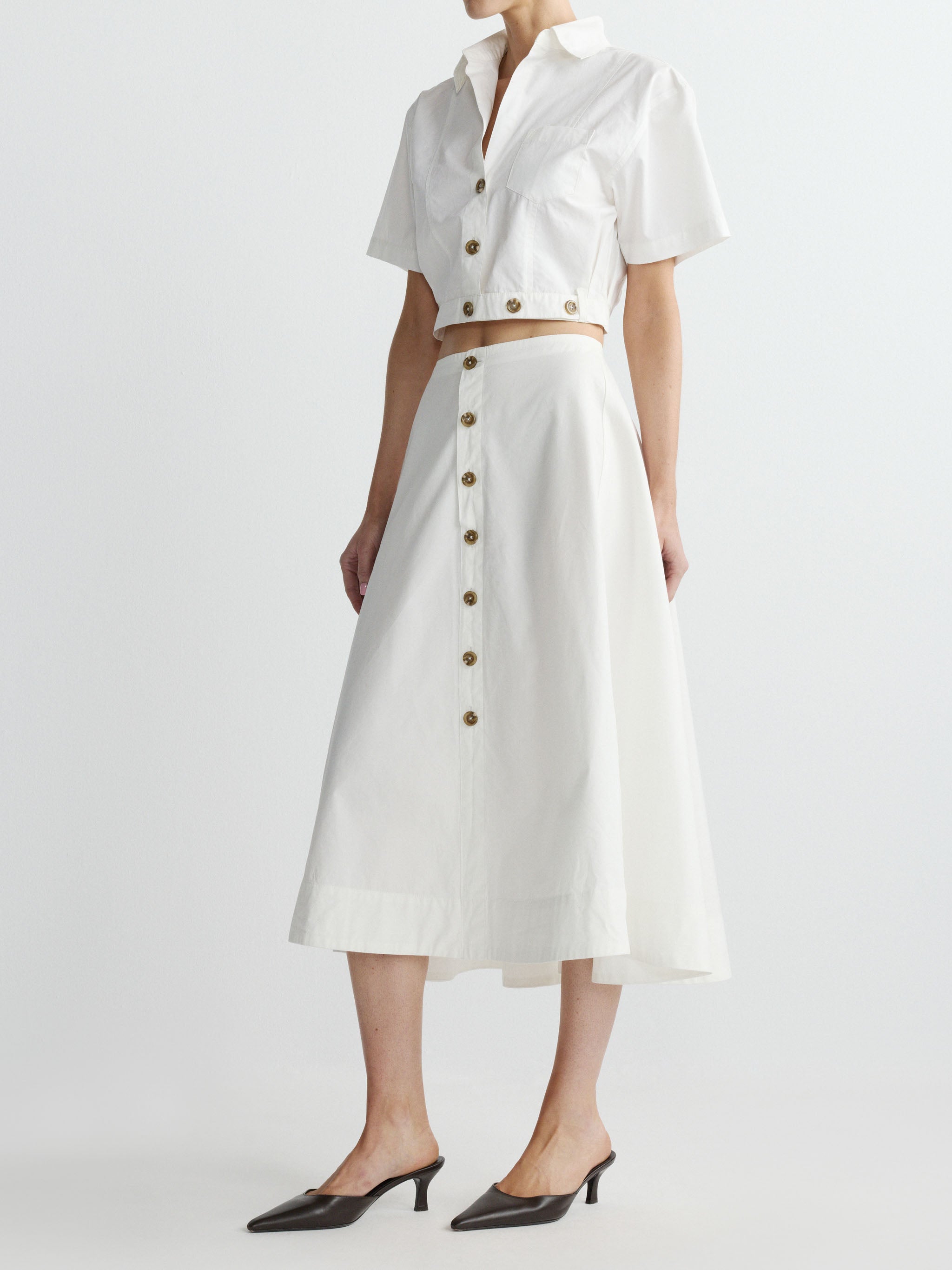 Person wearing a white outfit with button details on a plain background