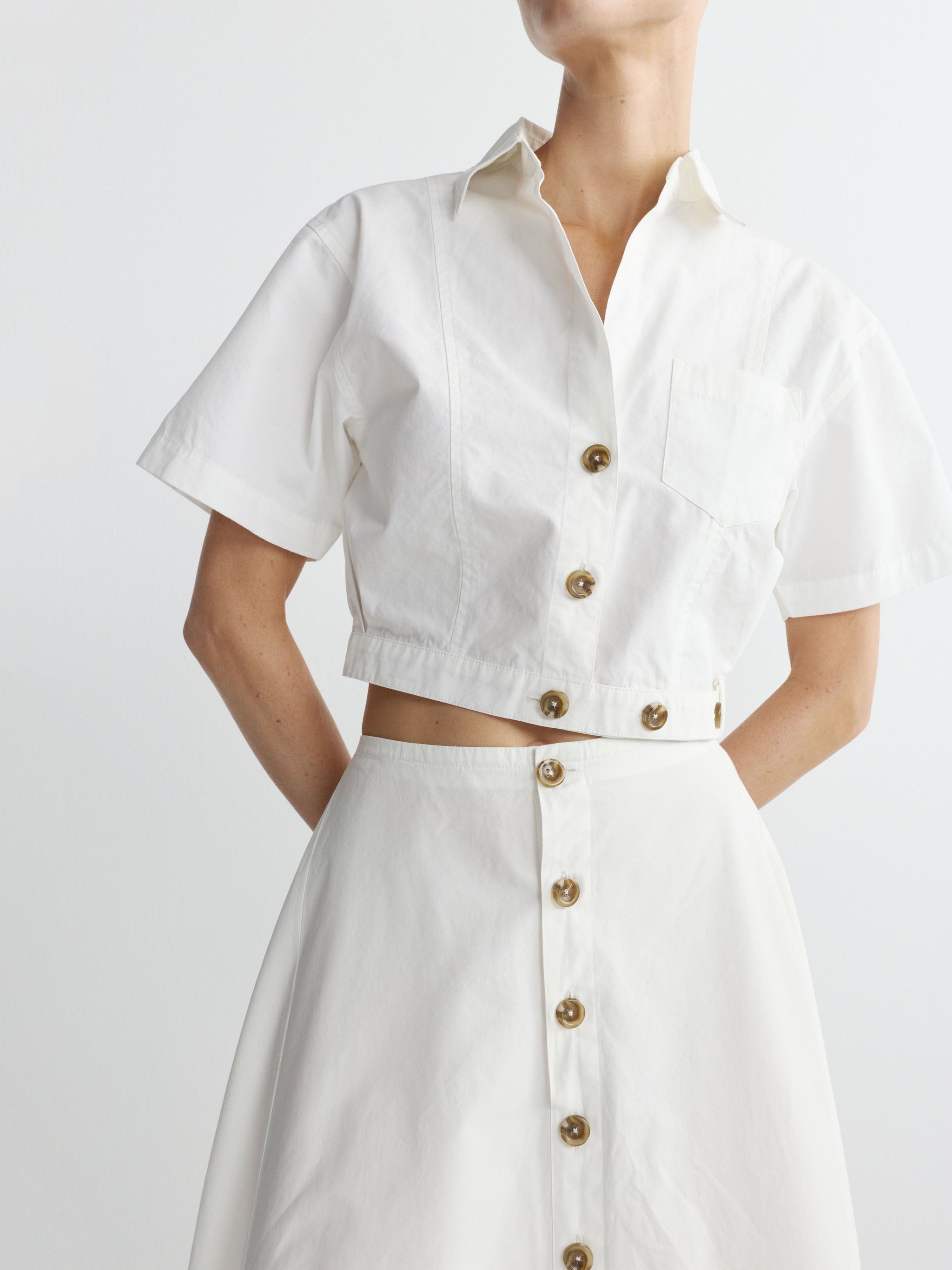 White button-up shirt and skirt set on a plain background