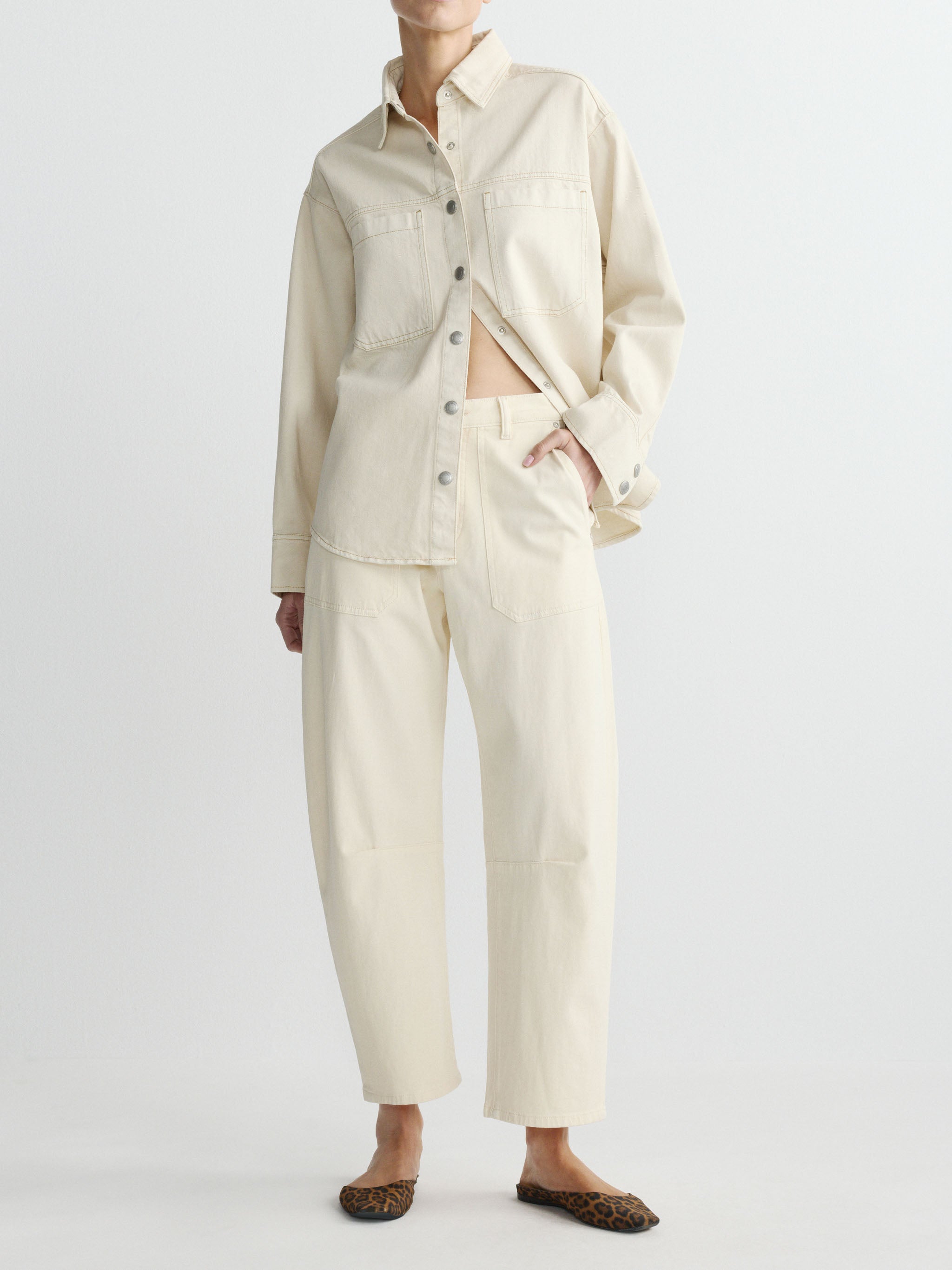 Person wearing a beige outfit with a shirt and pants on a white background