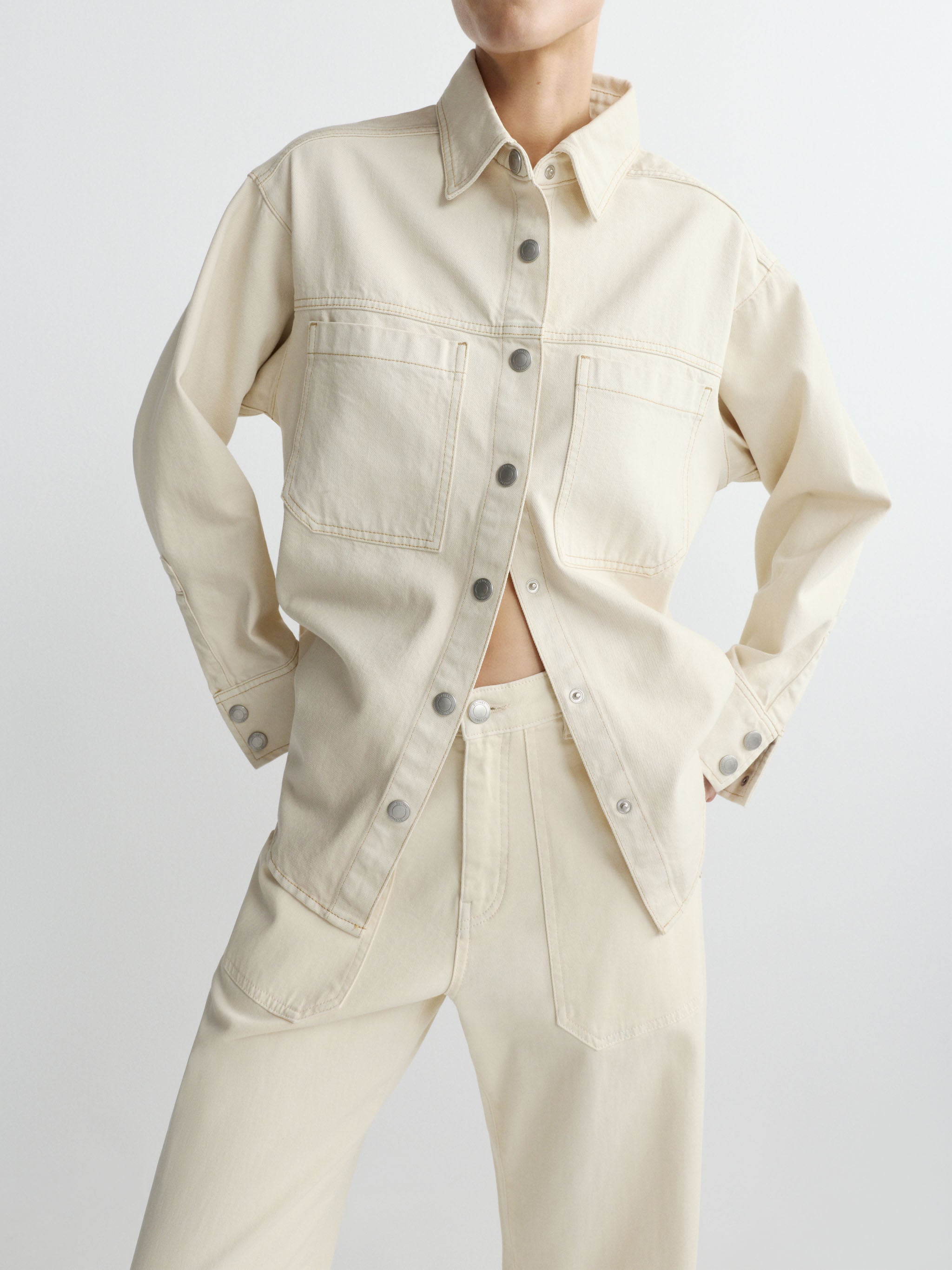 Person wearing a beige denim shirt and pants on a white background