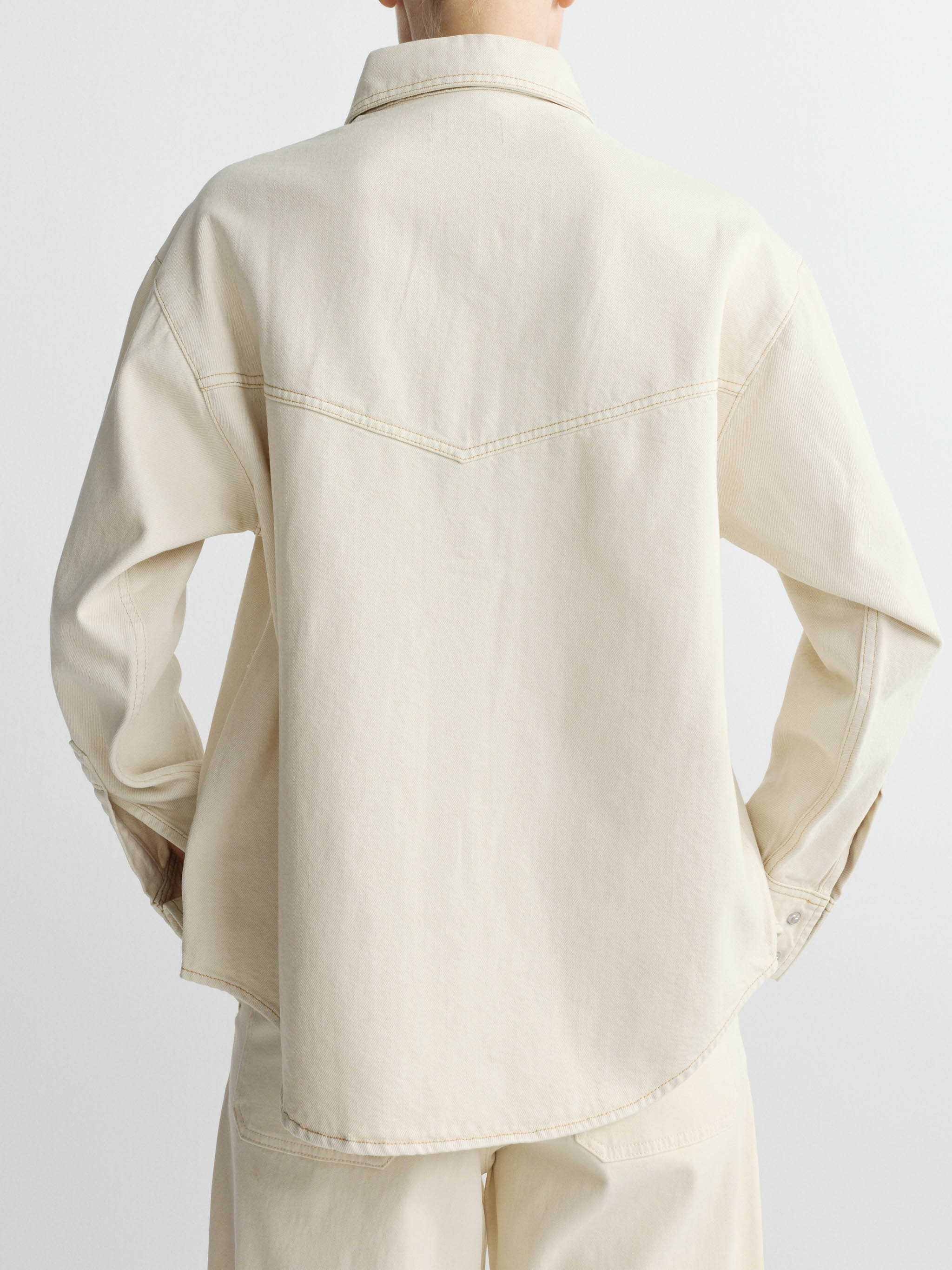 Beige shirt worn by a person on a white background