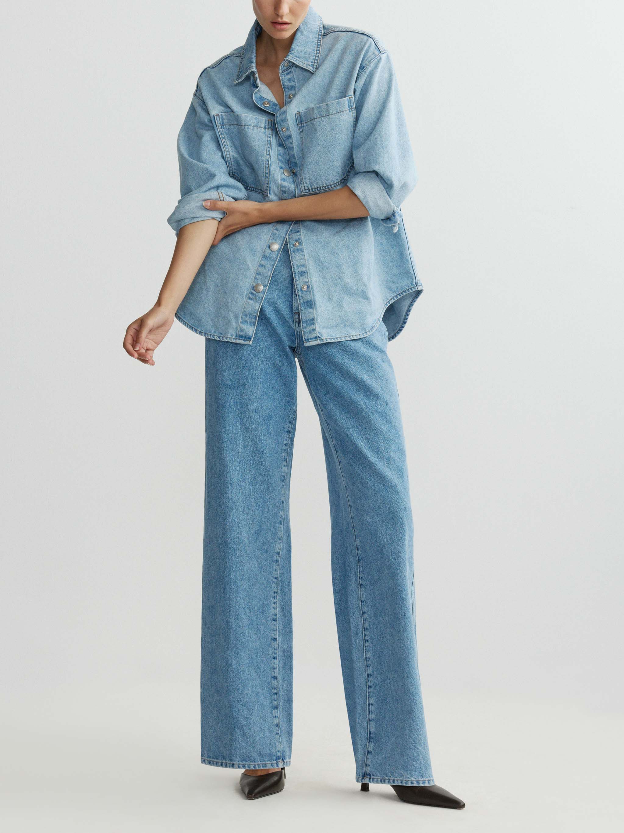 Person wearing a light blue denim outfit on a white background