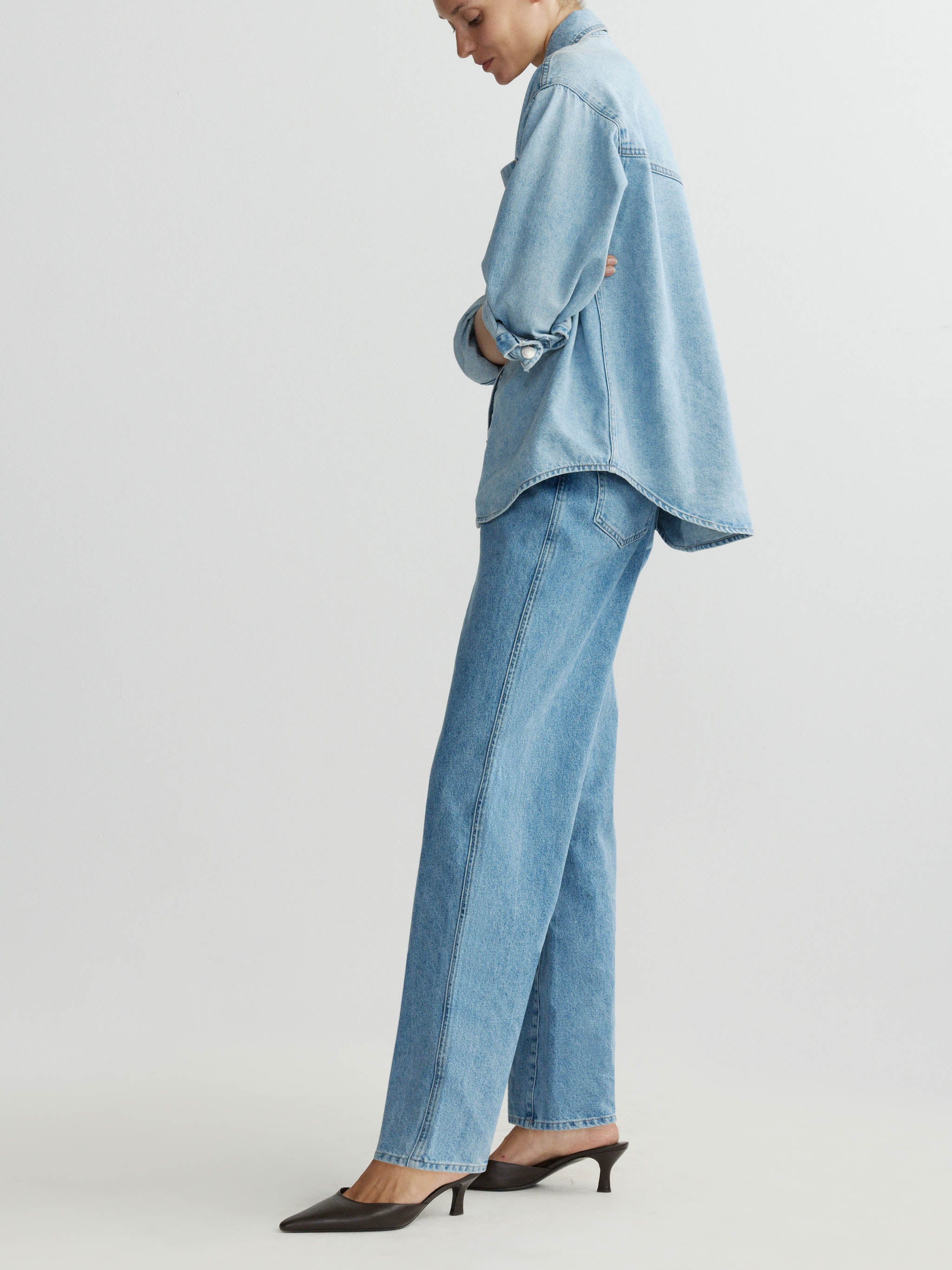 Person wearing a light blue denim outfit on a plain background