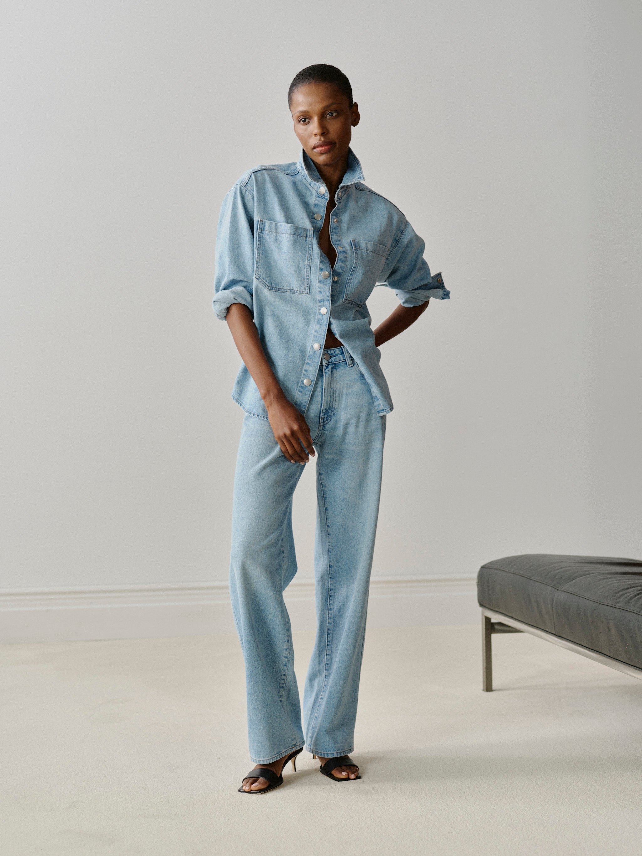 Person wearing a light blue denim outfit in a minimalistic setting