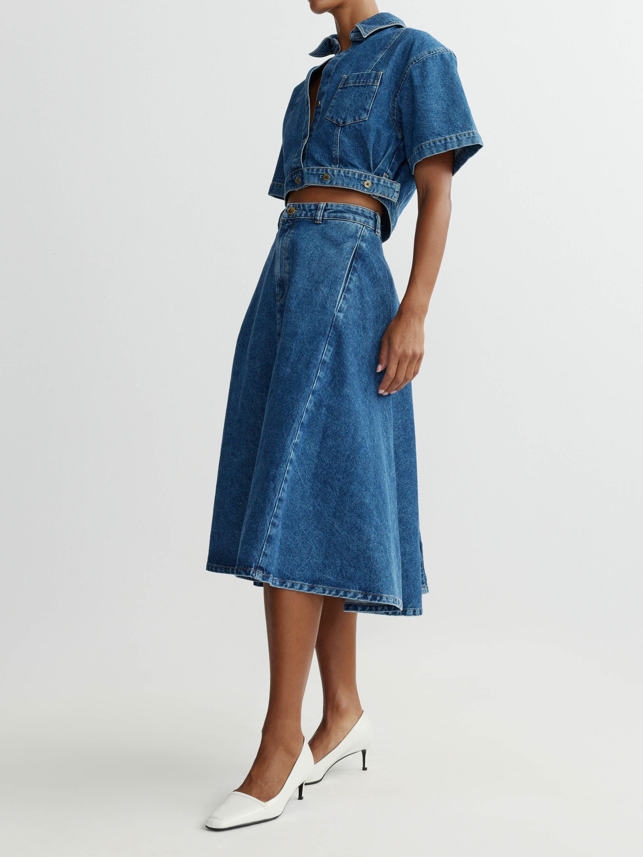 Person wearing a denim outfit with a skirt and jacket on a white background