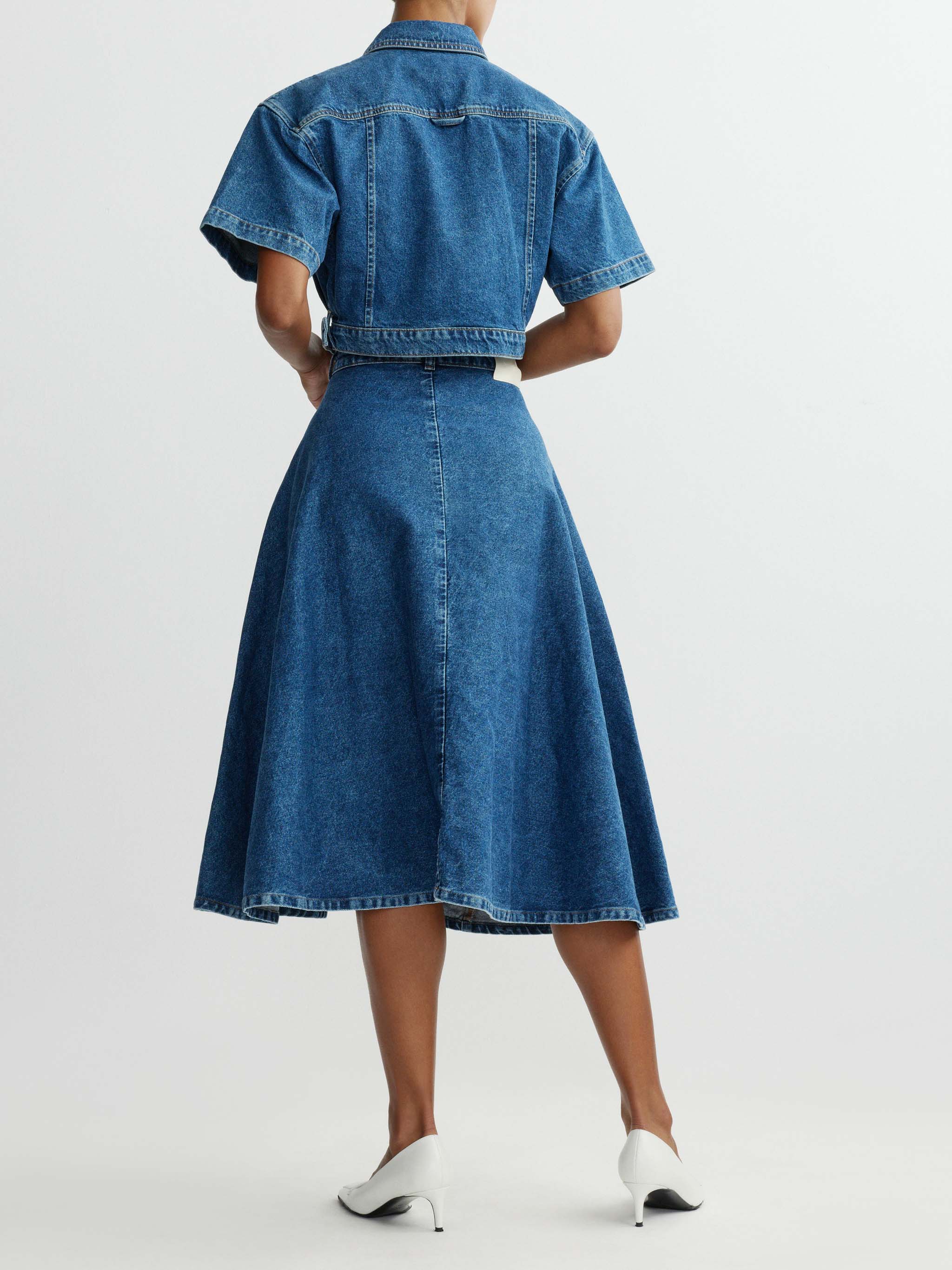 Person wearing a blue denim dress with a white background