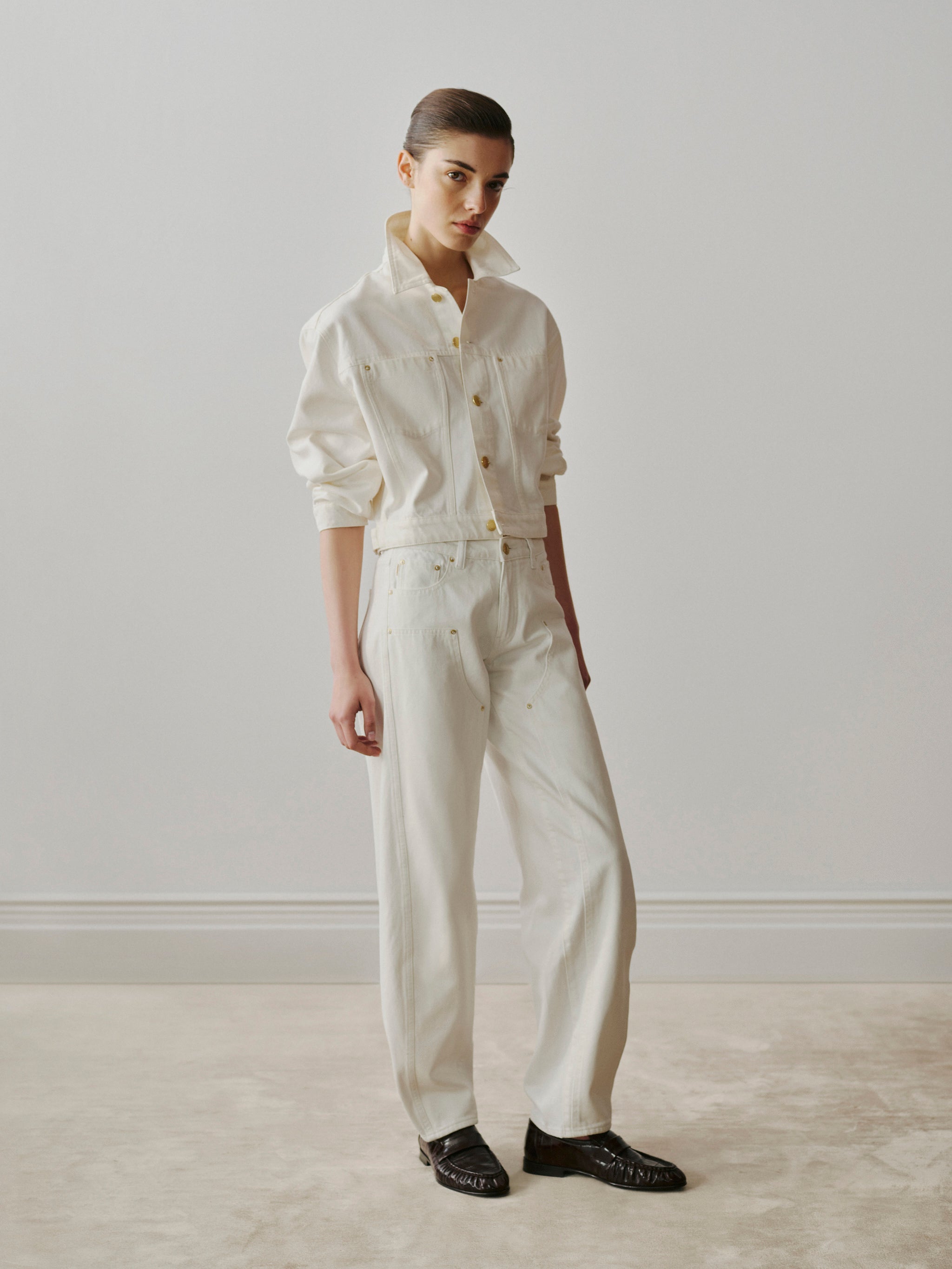 Person wearing a white denim outfit standing against a plain background