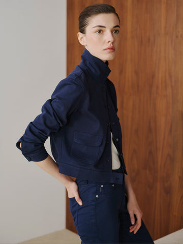 Person wearing a navy blue outfit against a wooden wall.