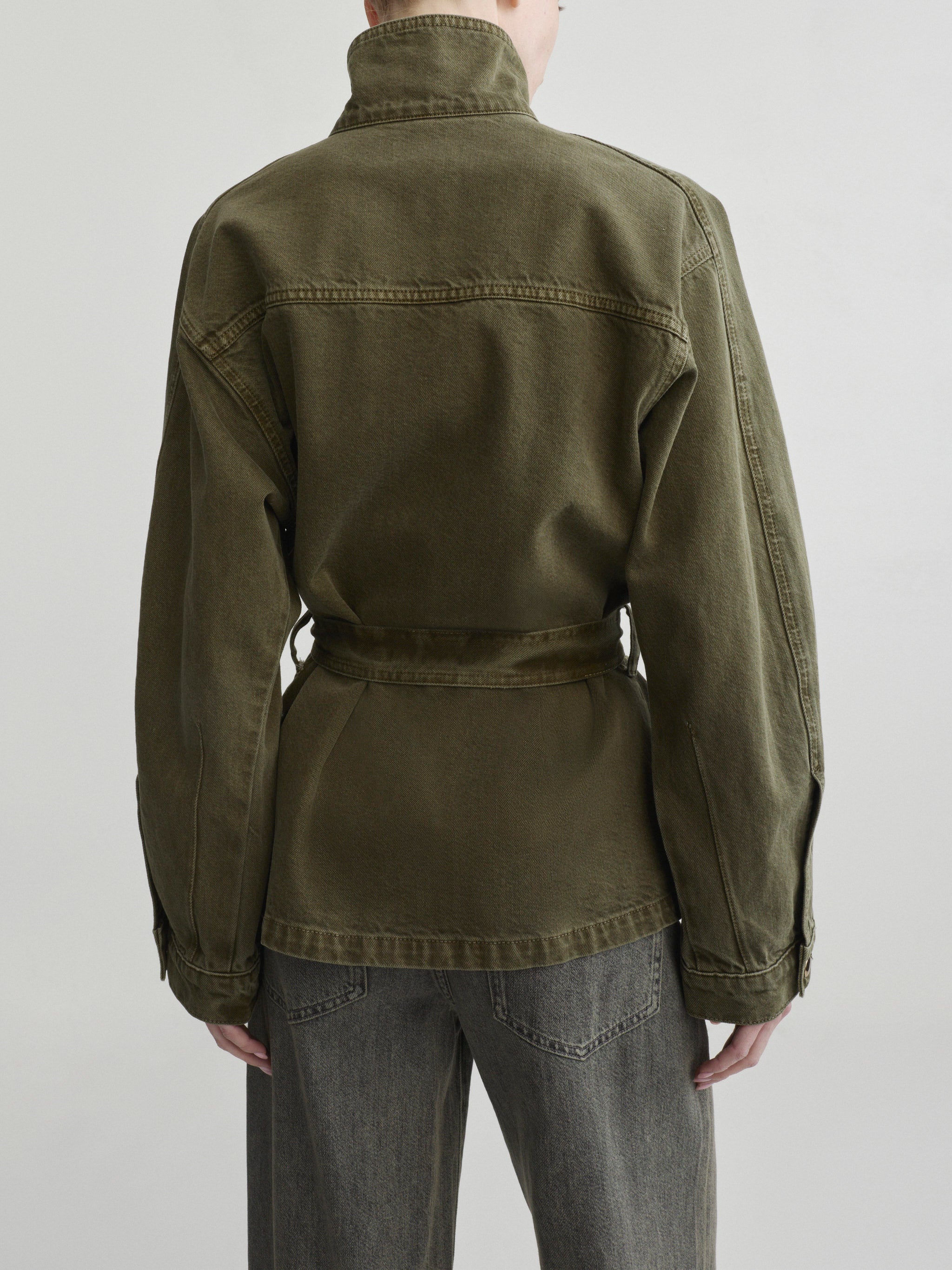 Shiloh Jacket in Pine on a model with grey jeans, studio back view close-up of collar and belt.