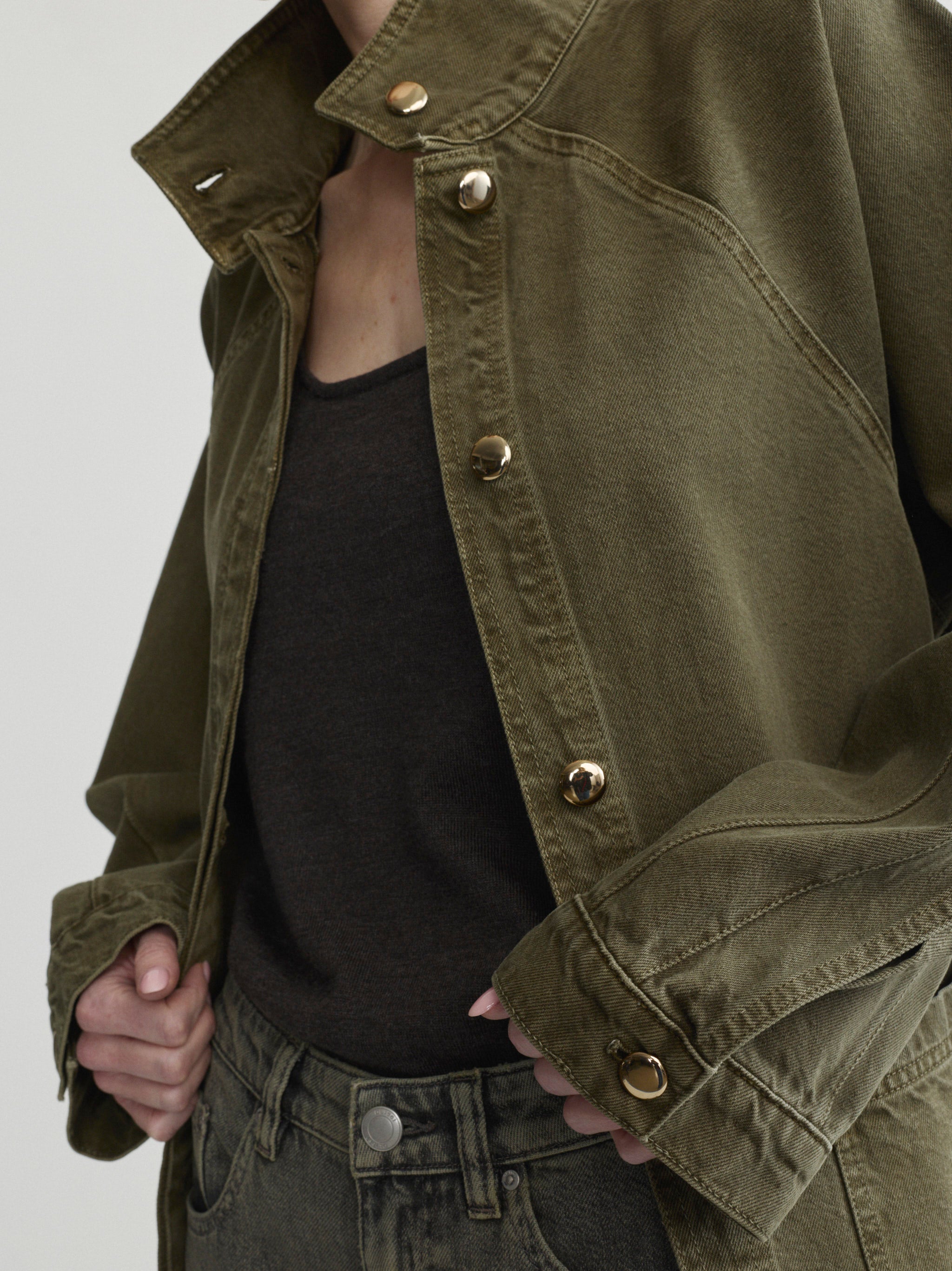 Shiloh Jacket in Pine over a black tank on a model, studio close-up of snap buttons.