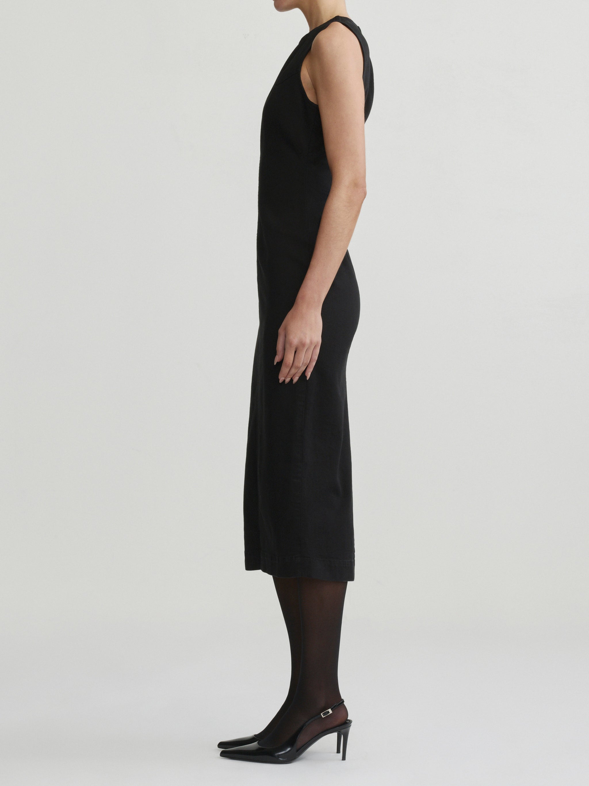 Esme Dress in Black on a model with sheer tights, studio full-length side profile view.