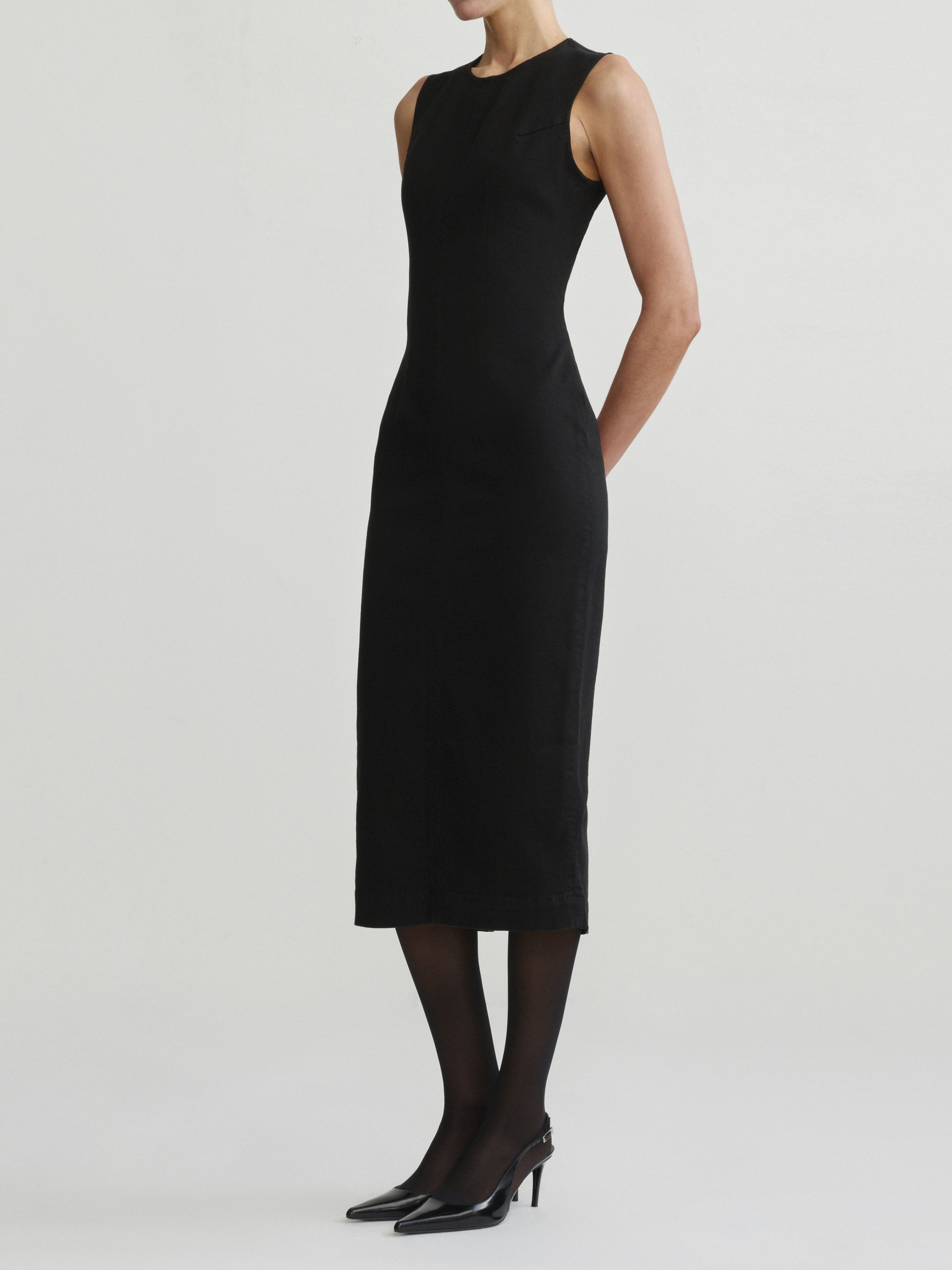 Esme Dress in Black on a model with sheer tights, studio full-length angled front view.