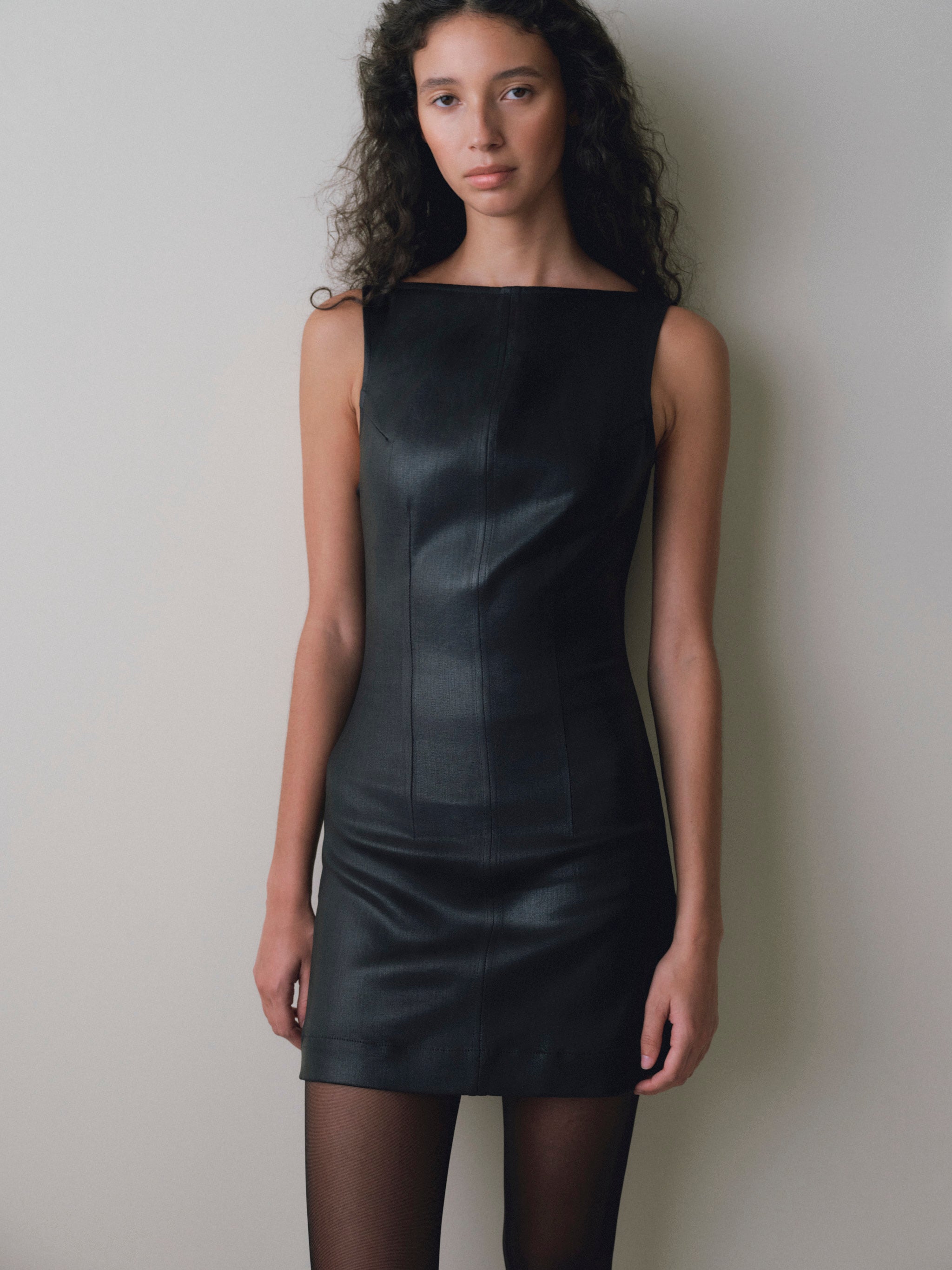 DL1961 women's Esme boat neck Instasculpt denim mini dress in 'Black Hawk Coated', front view with sheer black tights.