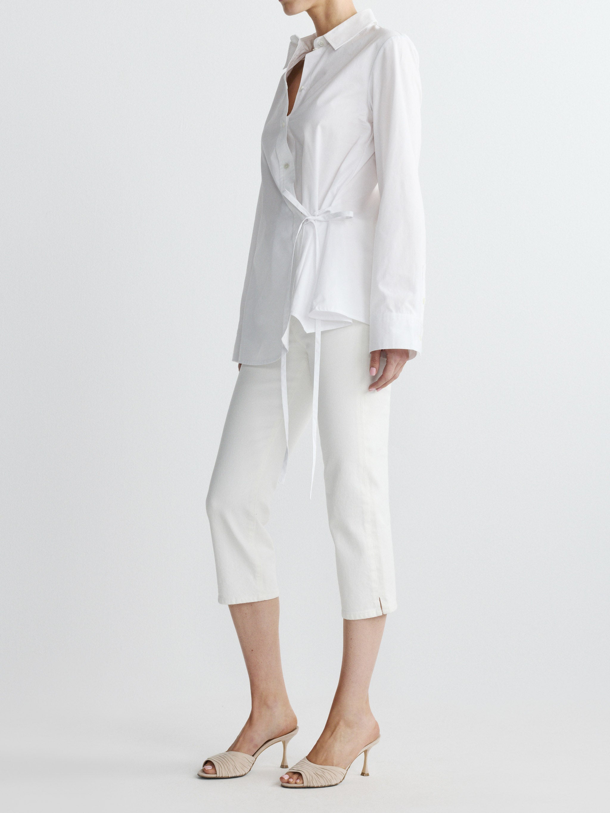 Person wearing a white outfit with a shirt and pants on a light gray background