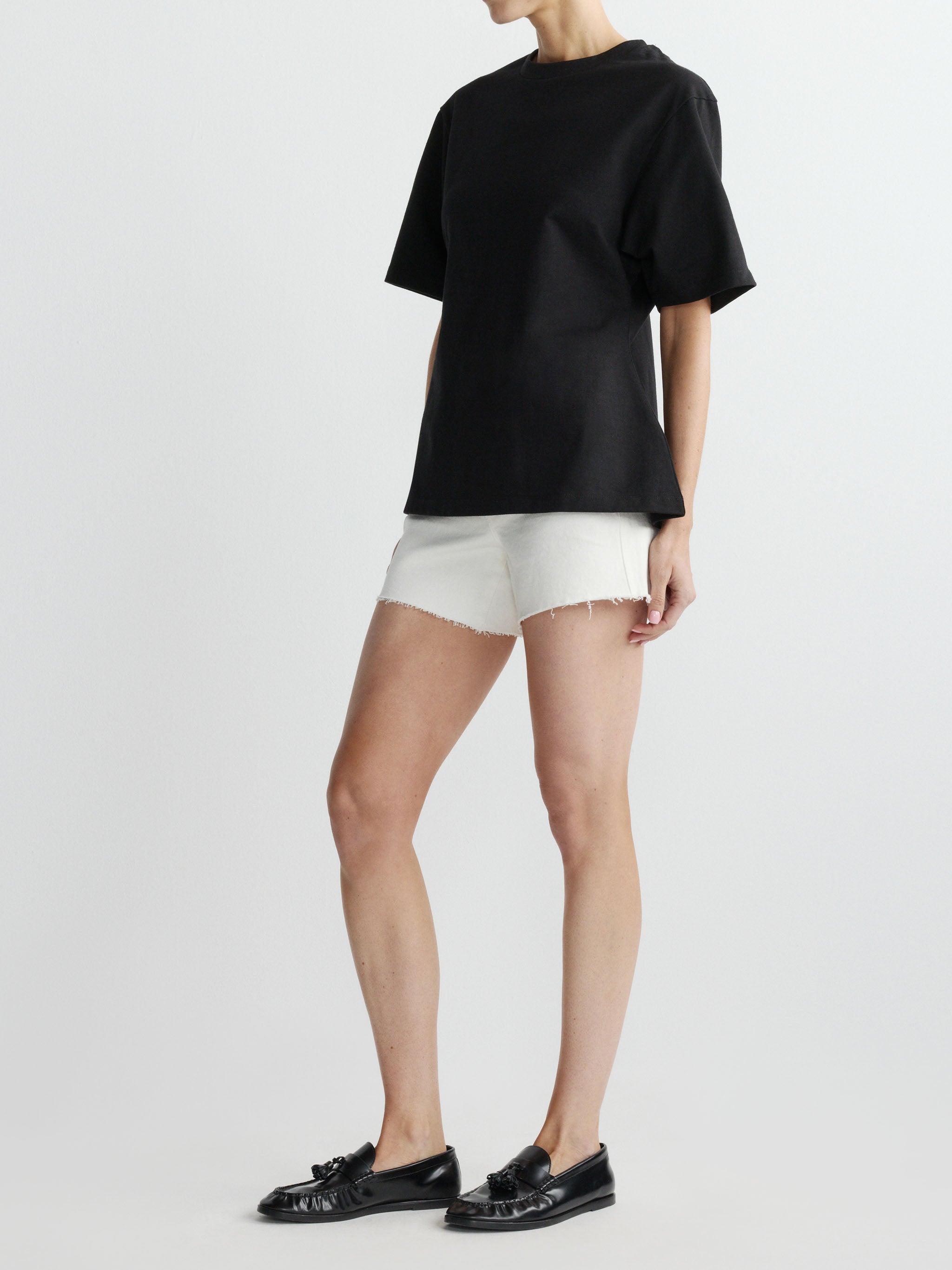 Person wearing a black top and white shorts on a plain background