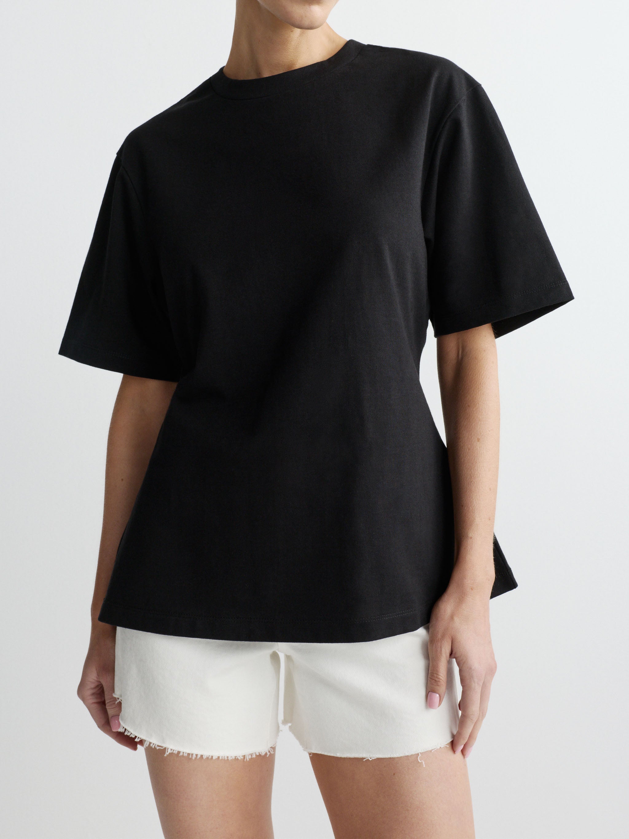 Person wearing a black t-shirt and white shorts on a plain background