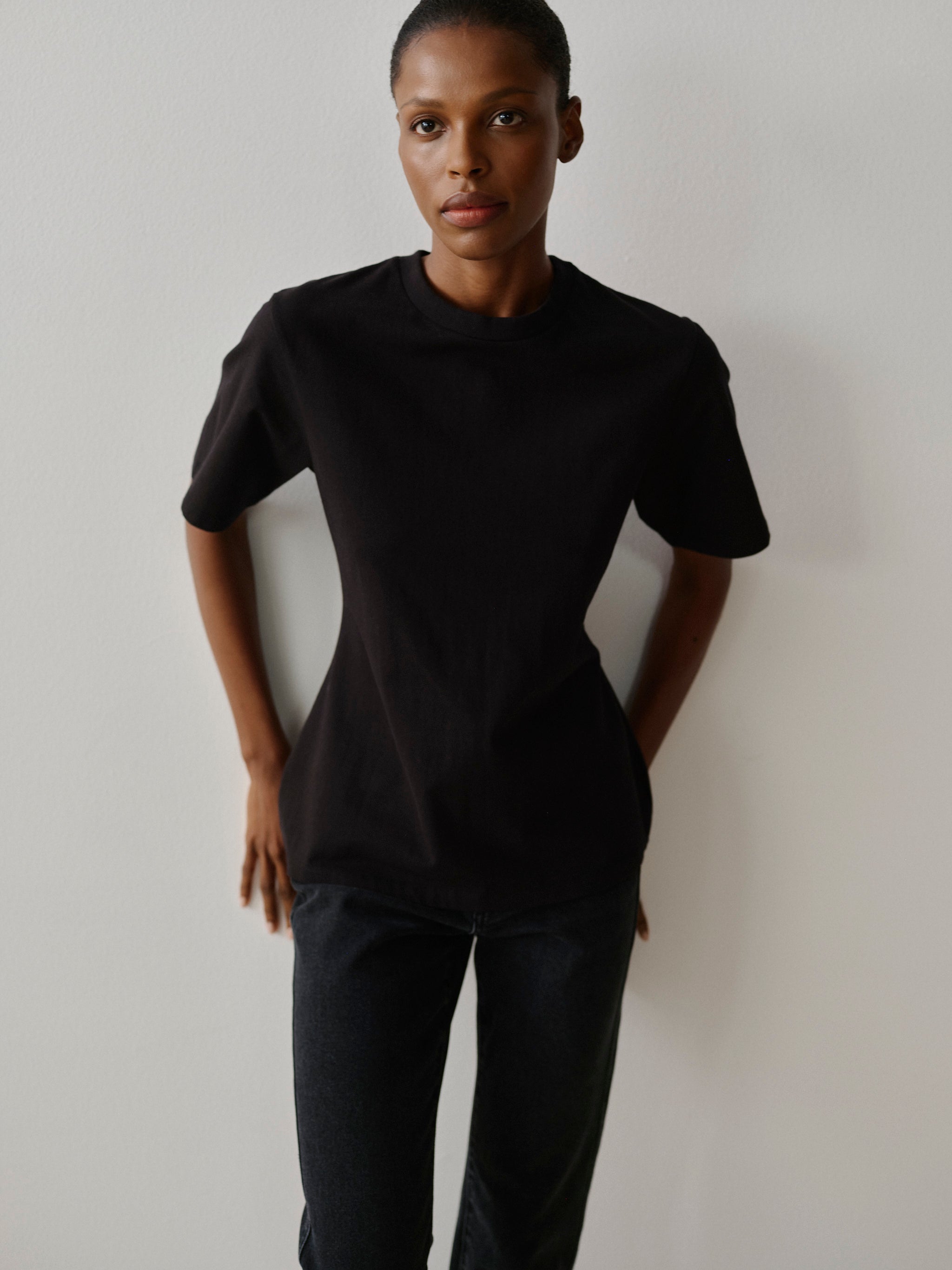 Person wearing a black outfit against a plain background