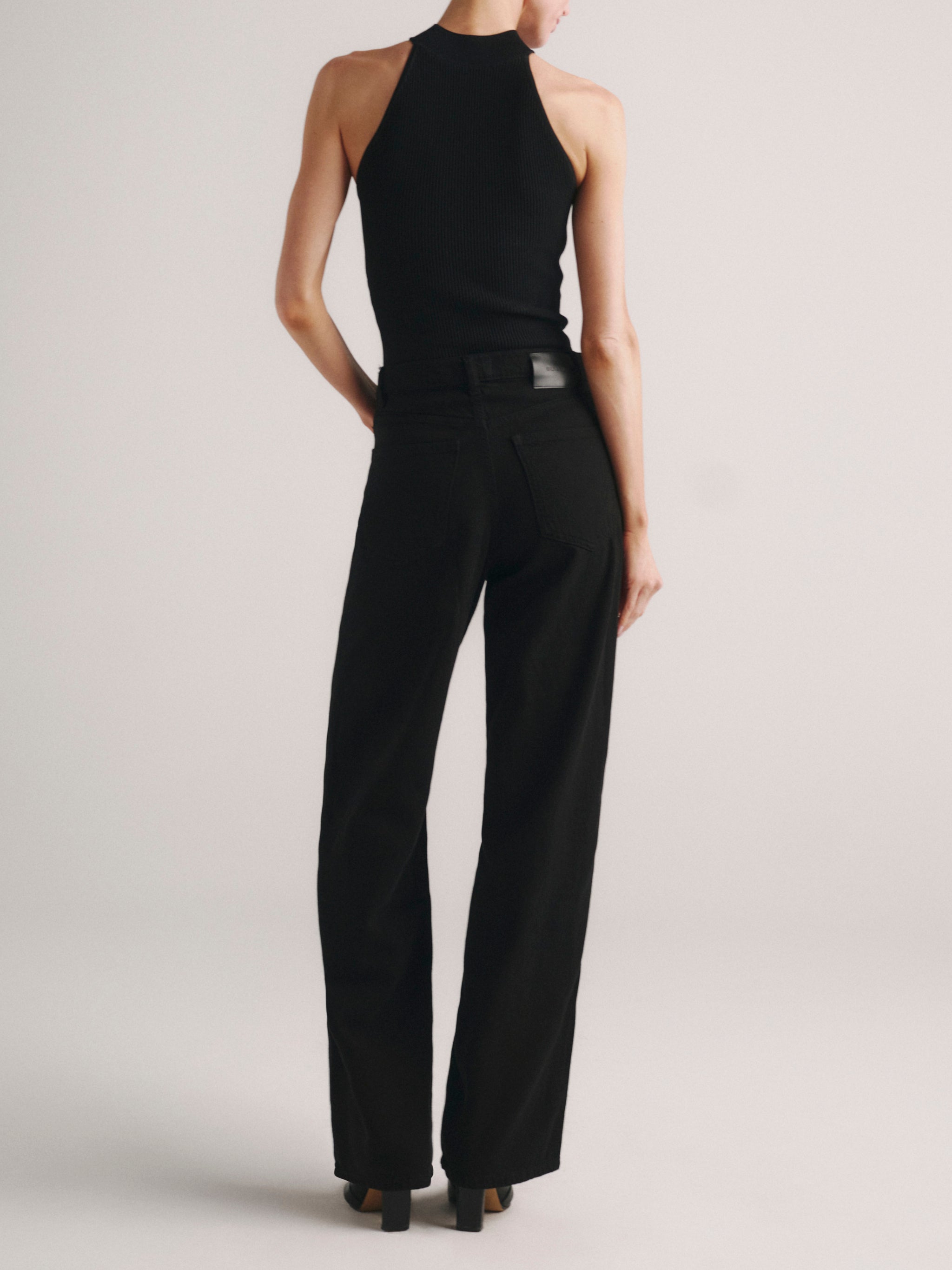 Mock Neck Top Instasculpt Rib in Black on a model with black jeans, studio full-length back view.