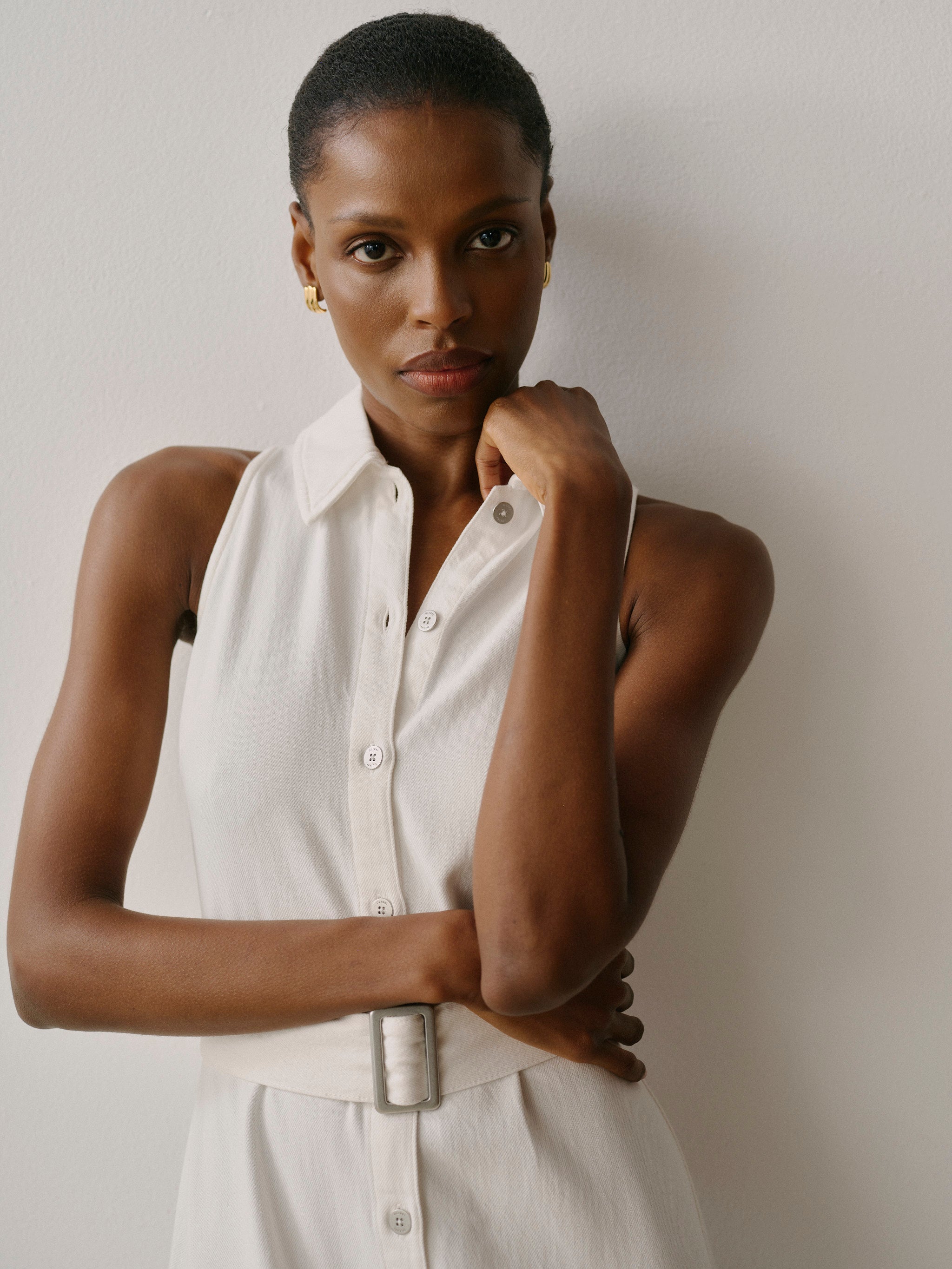 Woman wearing a white sleeveless shirt against a plain background