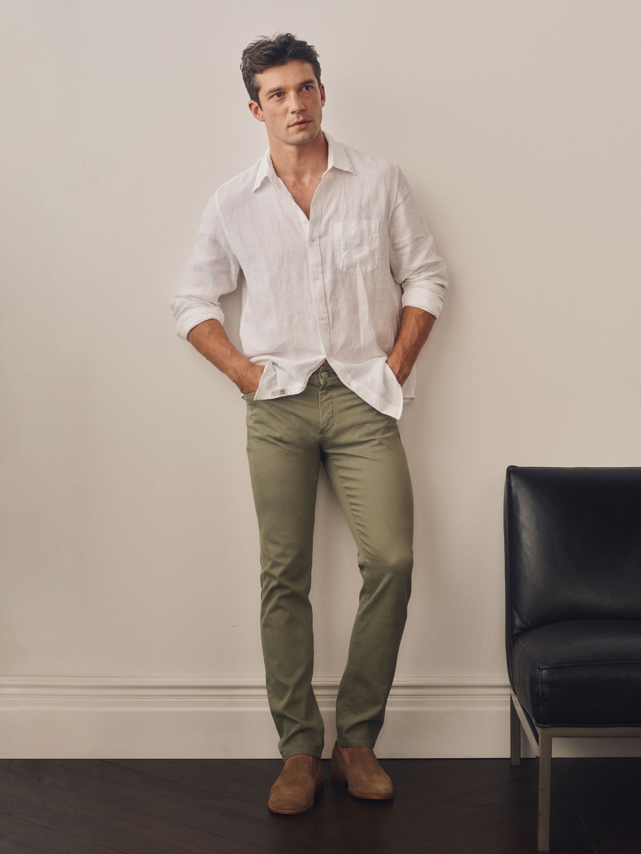 Person wearing a white button-up shirt and beige pants on a plain background