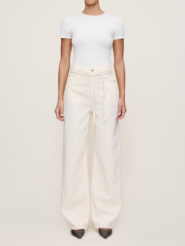 Person wearing a white t-shirt and cream-colored pants on a plain background