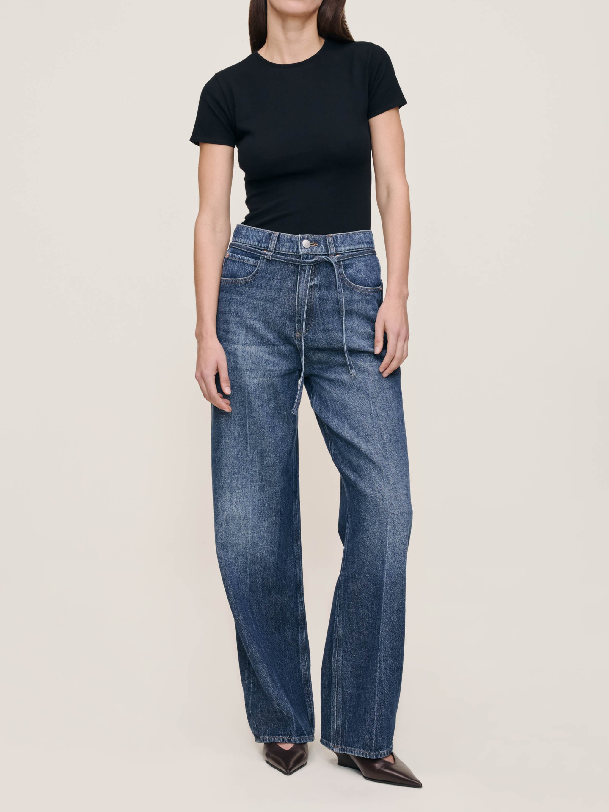 Person wearing blue jeans and a black t-shirt on a white background